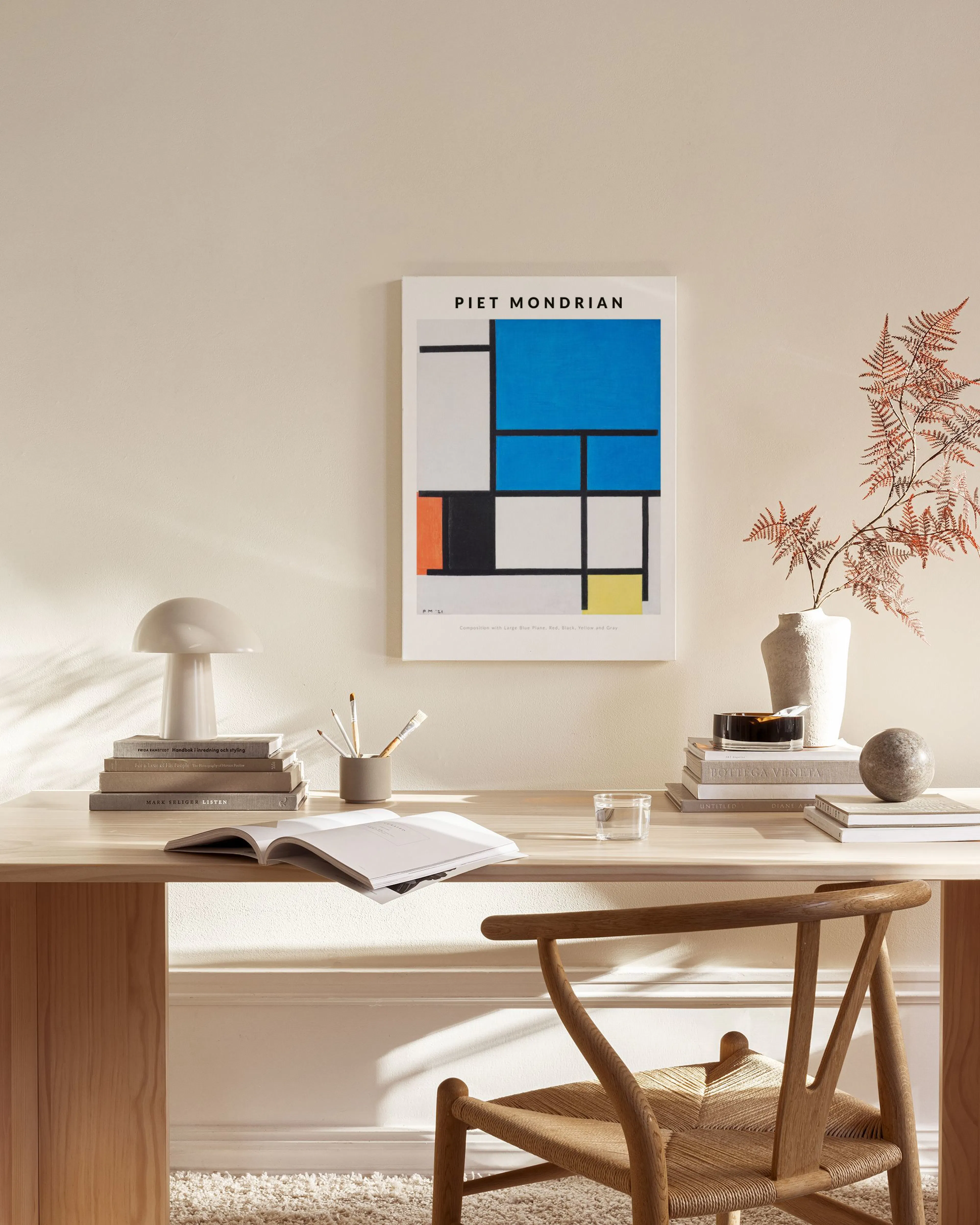 Canvas met Mondriaan-print in een modern interieur, boven een houten meubel en naast een stoel.