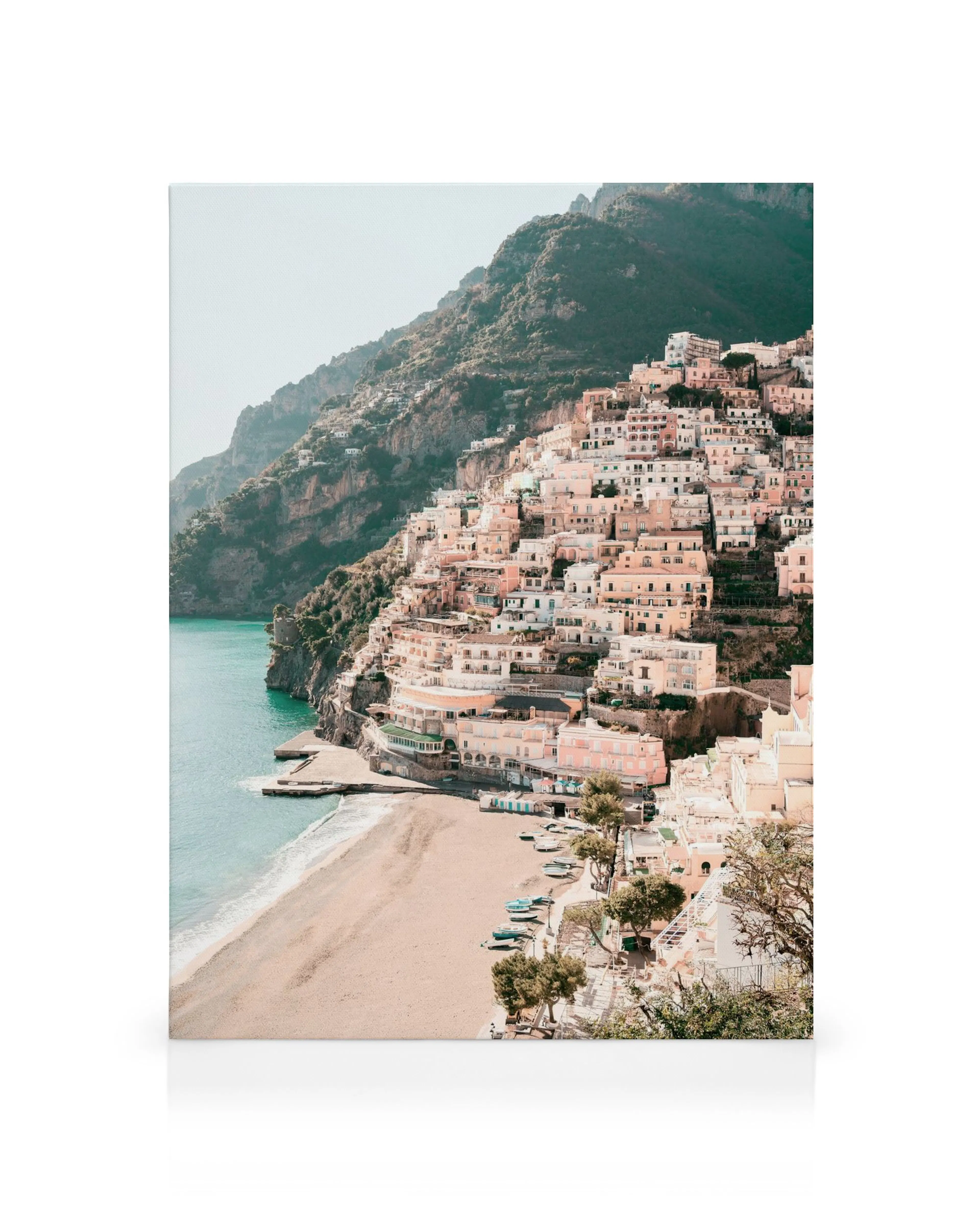 Positano coastal town canvas print, with pastel buildings cascading down to a sandy beach. Blue ocean and green mountains.