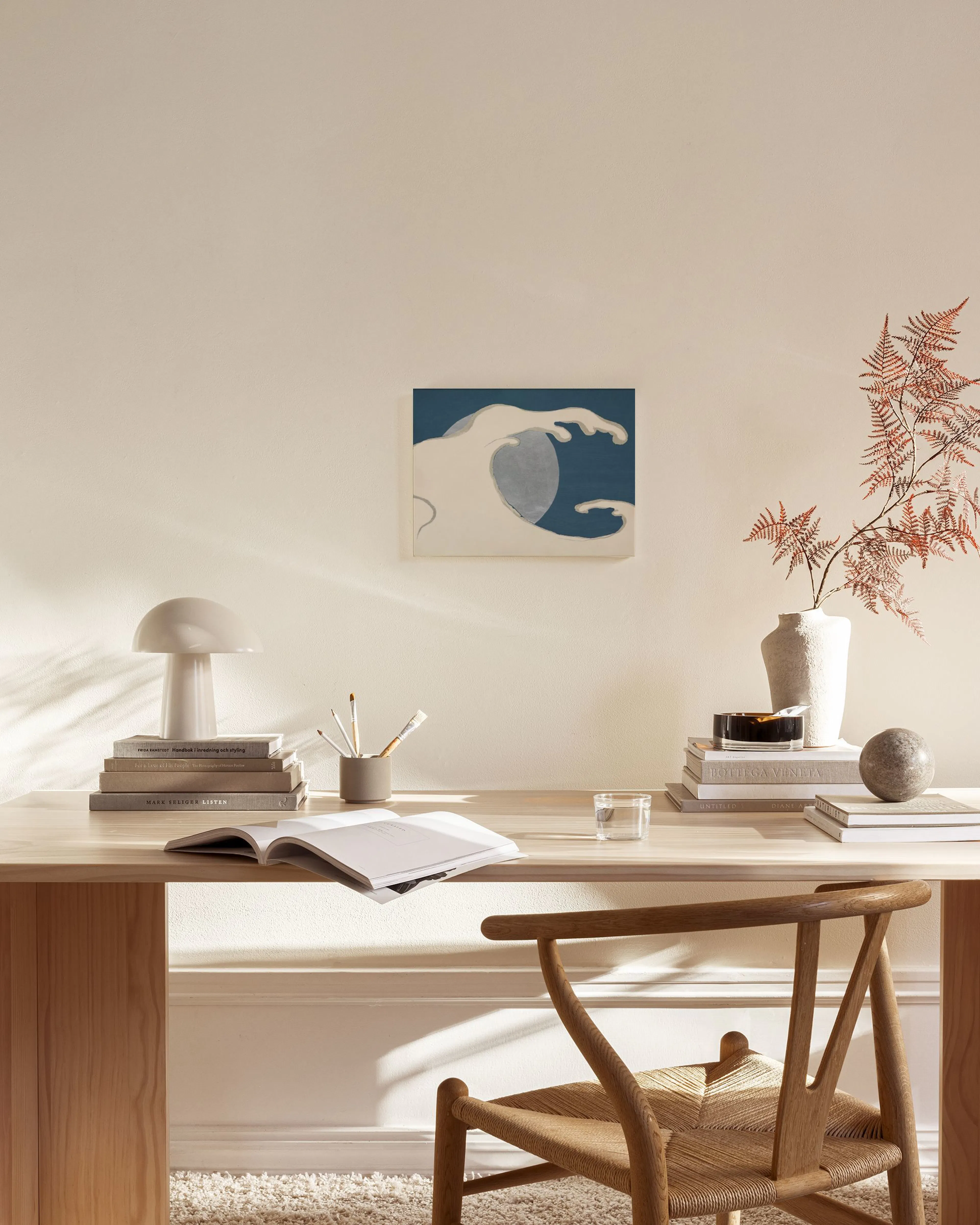 Toile murale décorative dune vague blanche et bleue, suspendue au-dessus dun meuble bas dans un salon moderne.