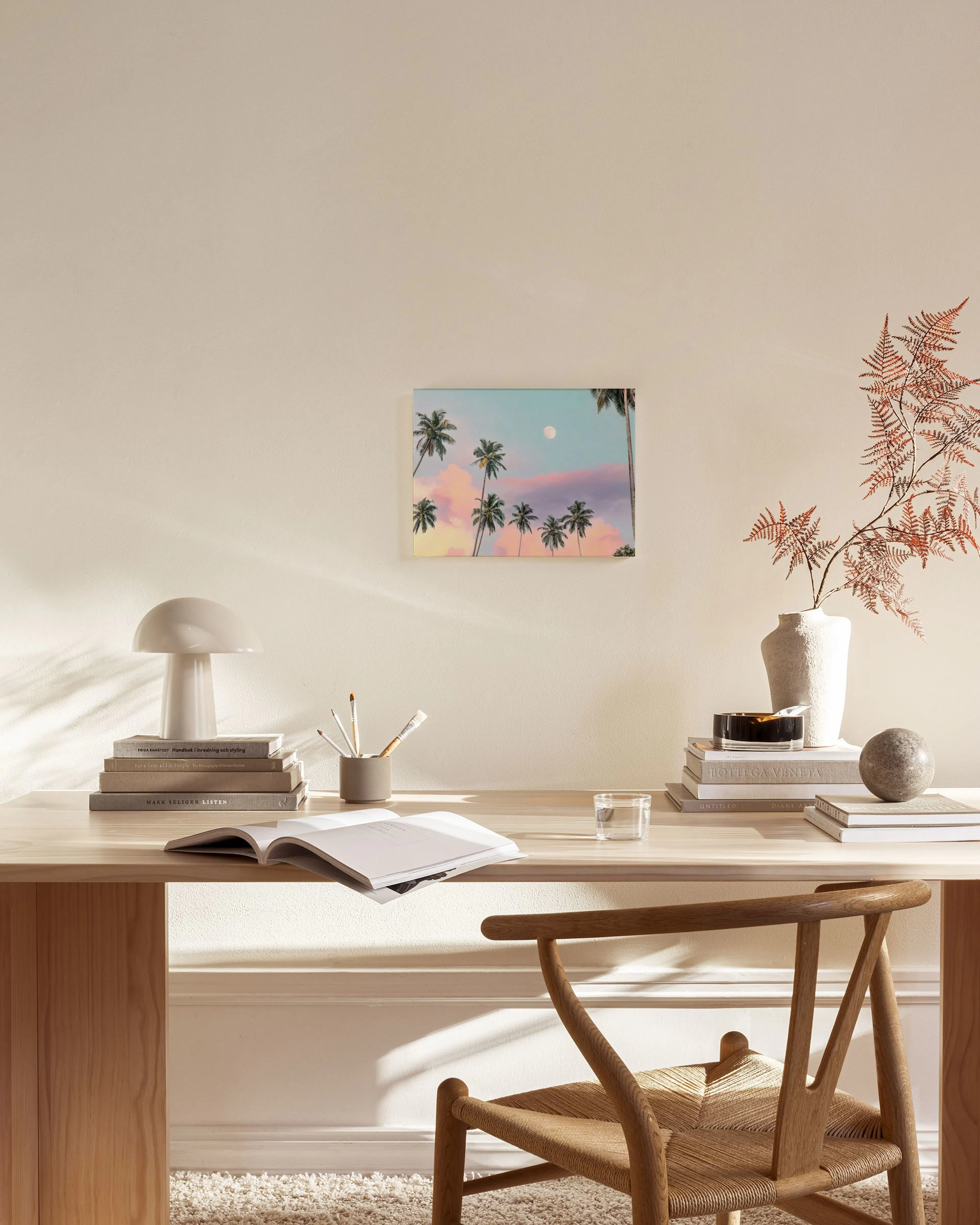 Leinwandbild mit Palmen und Mond vor rosa-blauem Himmel, hängend in einem modernen Wohnzimmer über einem Sideboard.