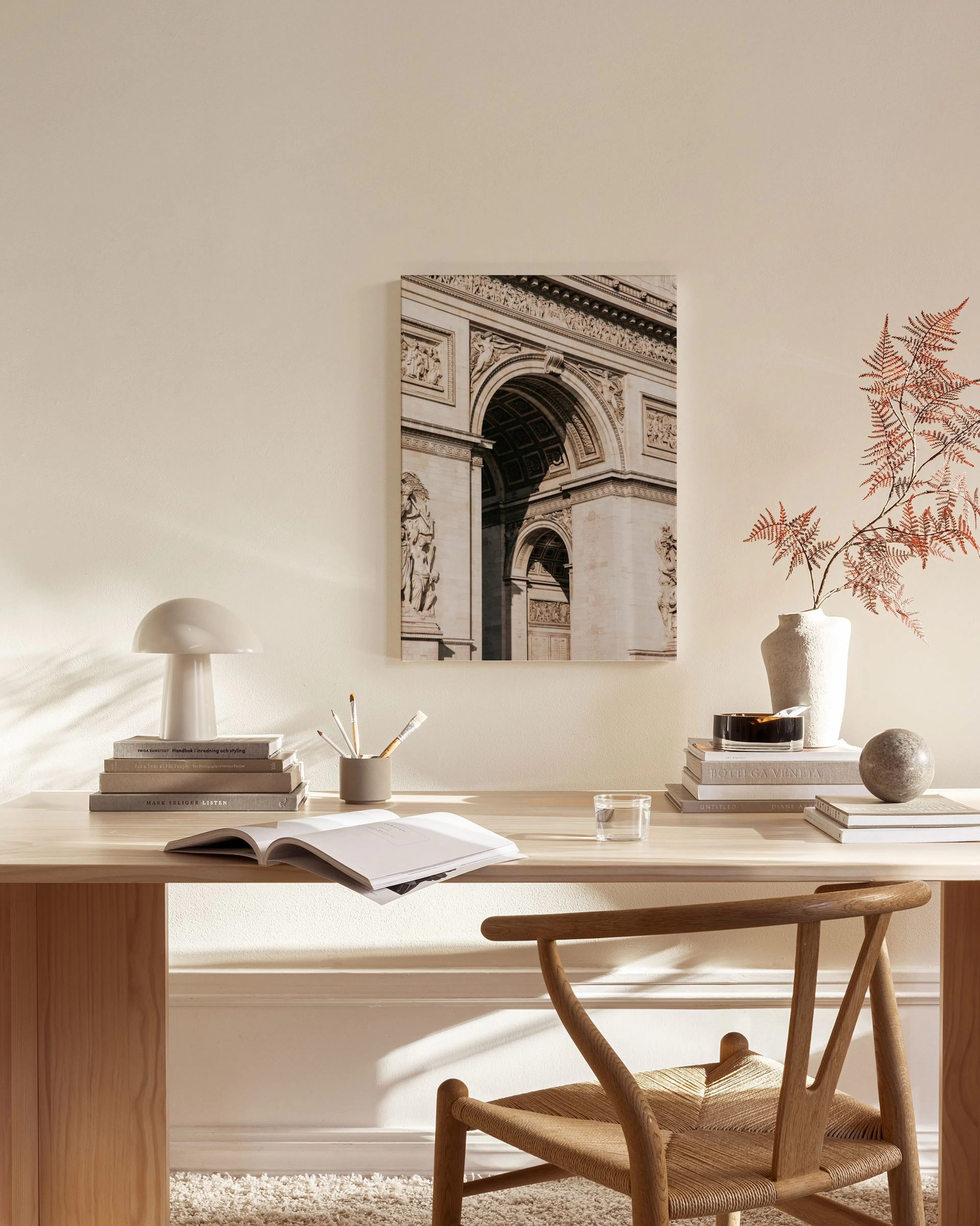 Leinwandbild des Arc de Triomphe in Paris, hängend über einem Sideboard in einem hellen Wohnzimmer.