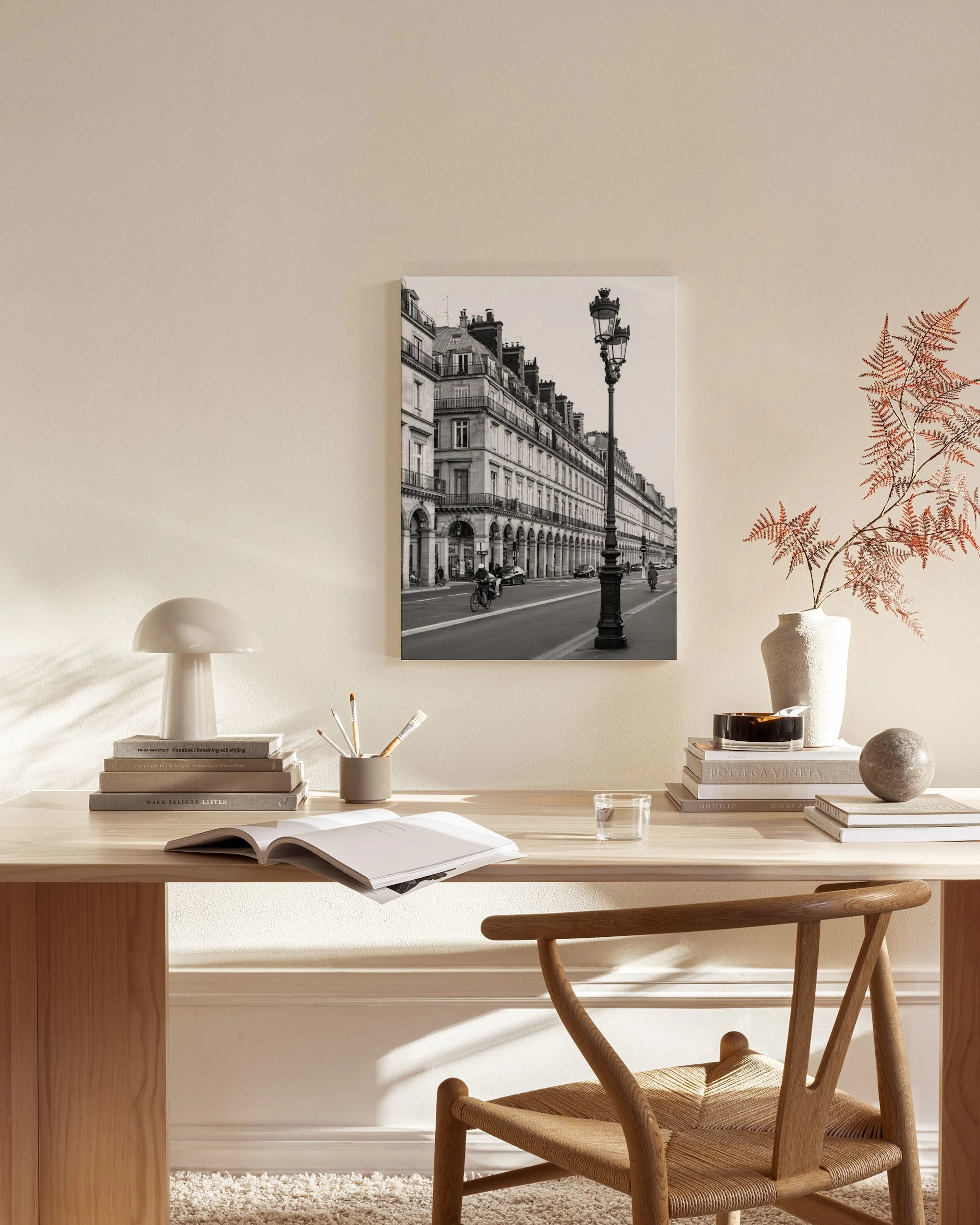 A black and white canvas print of a classic Parisian street with a lamppost, hanging in a minimalist living room.