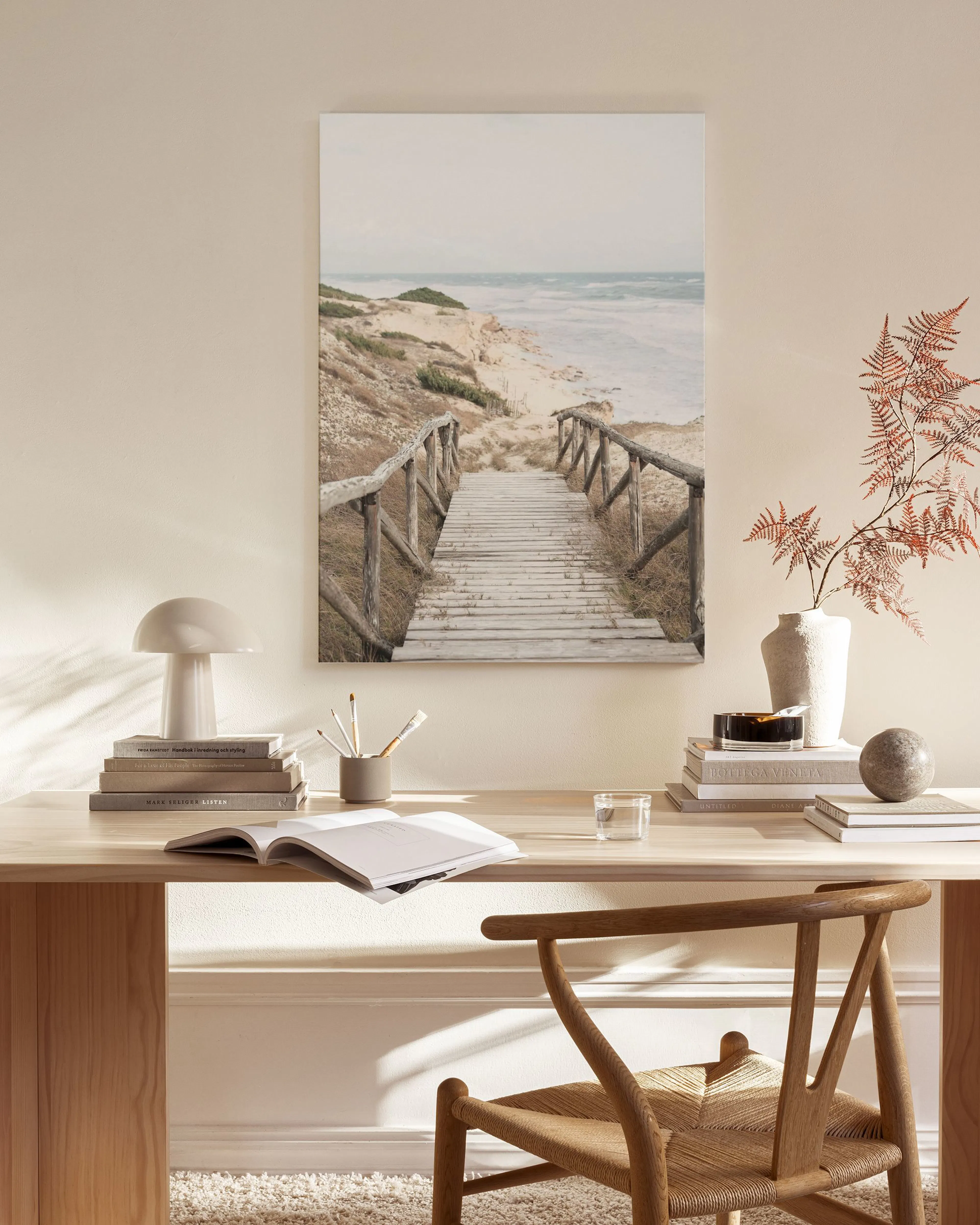 A canvas print of a wooden boardwalk leading to a sandy beach and ocean, displayed in a bright living room.