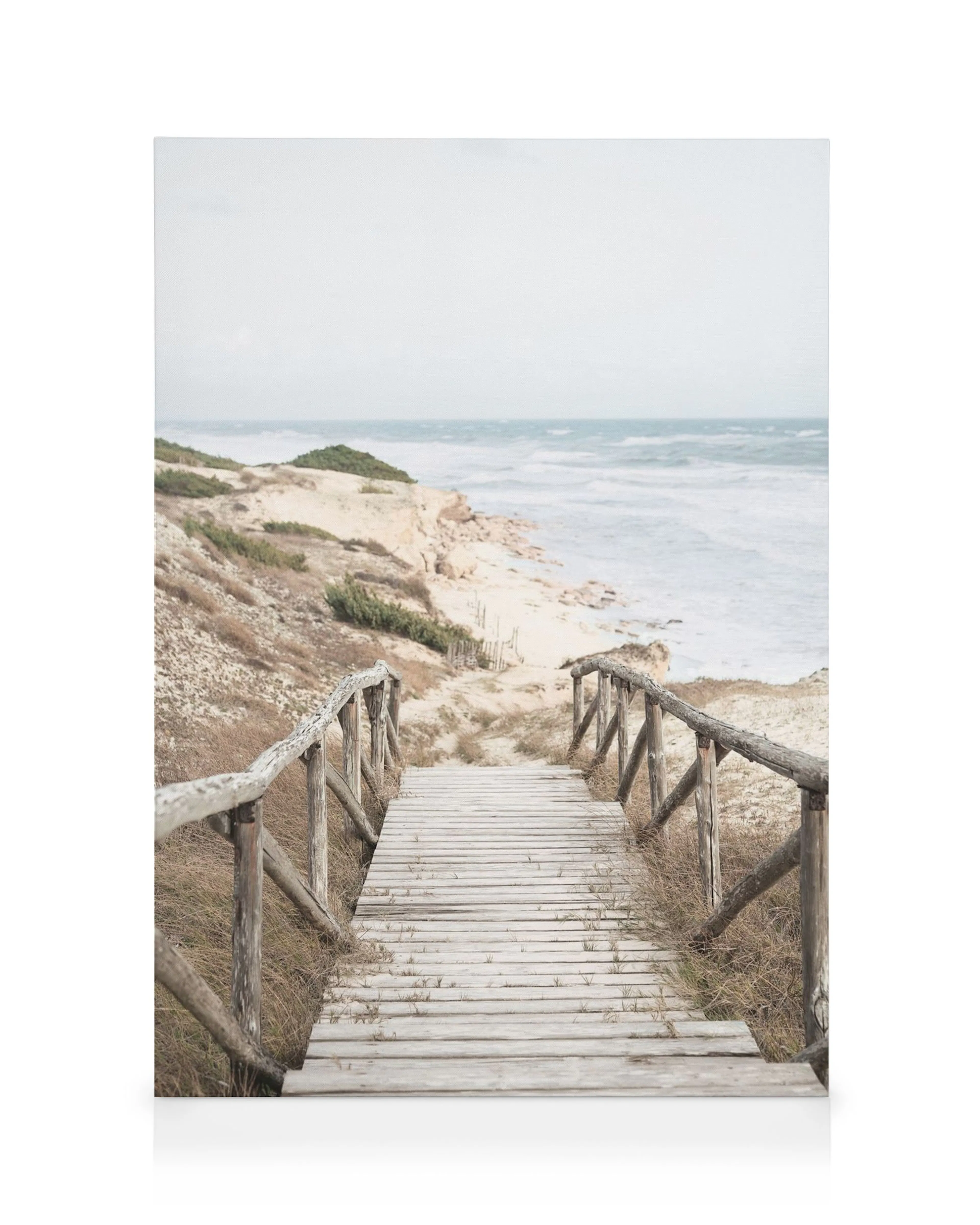 Sendero de madera en la playa de Hamptons, con dunas beige y mar agitado. Fotografía de paisaje.