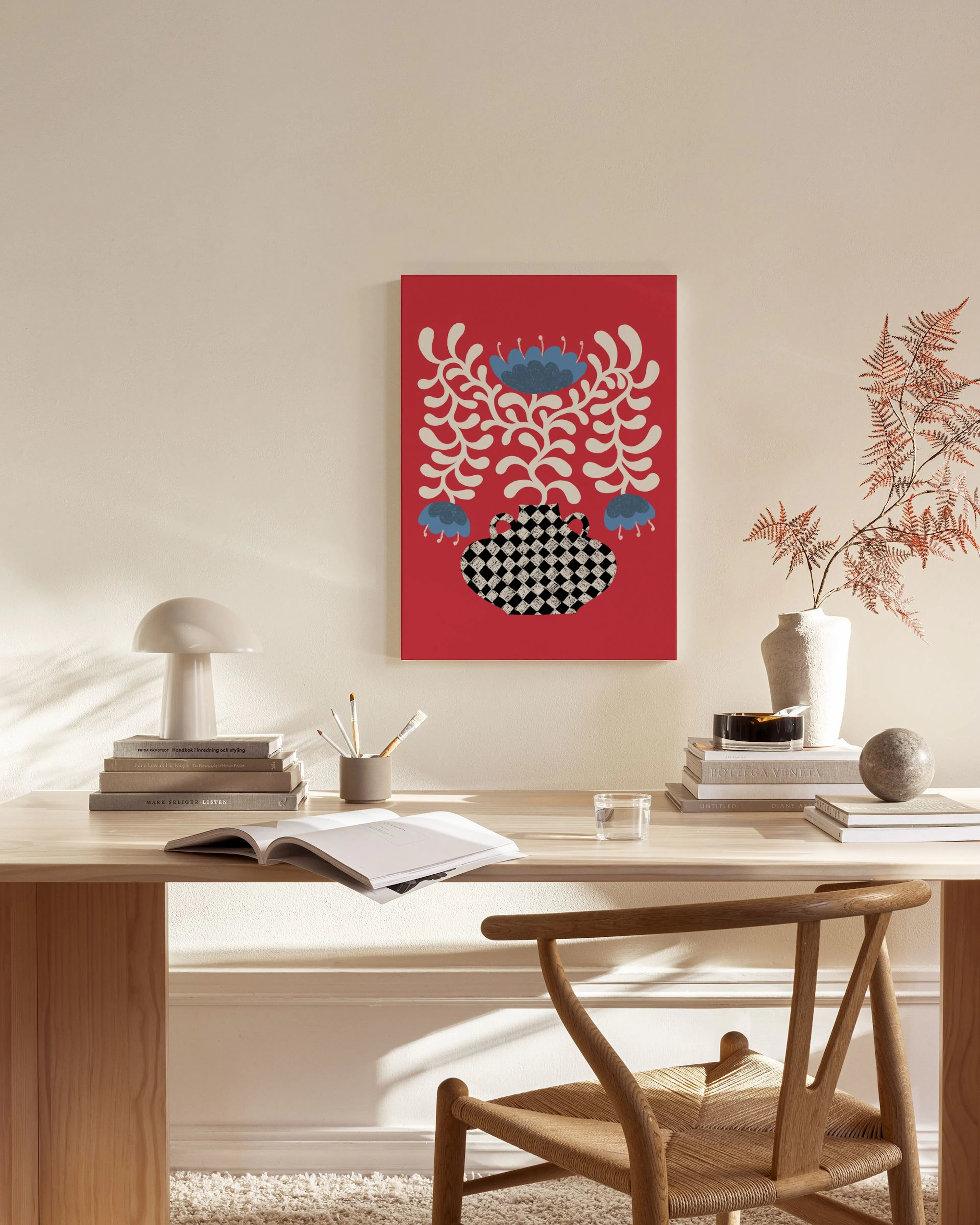 A canvas print of a red background with a black and white checkered vase and blue flowers, hanging in a modern living room.