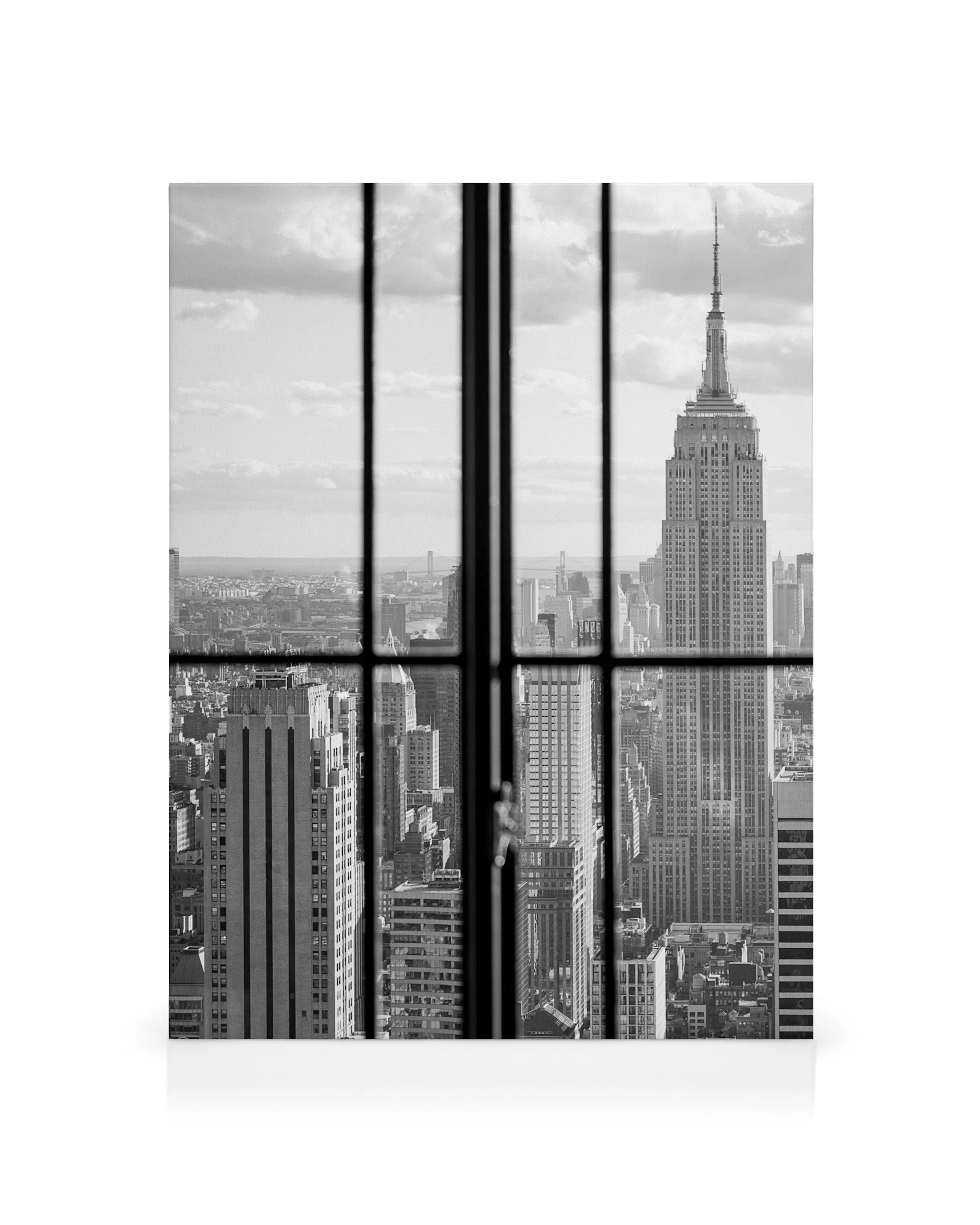 Black and white Manhattan skyline through a window, featuring the iconic Empire State Building and city architecture.