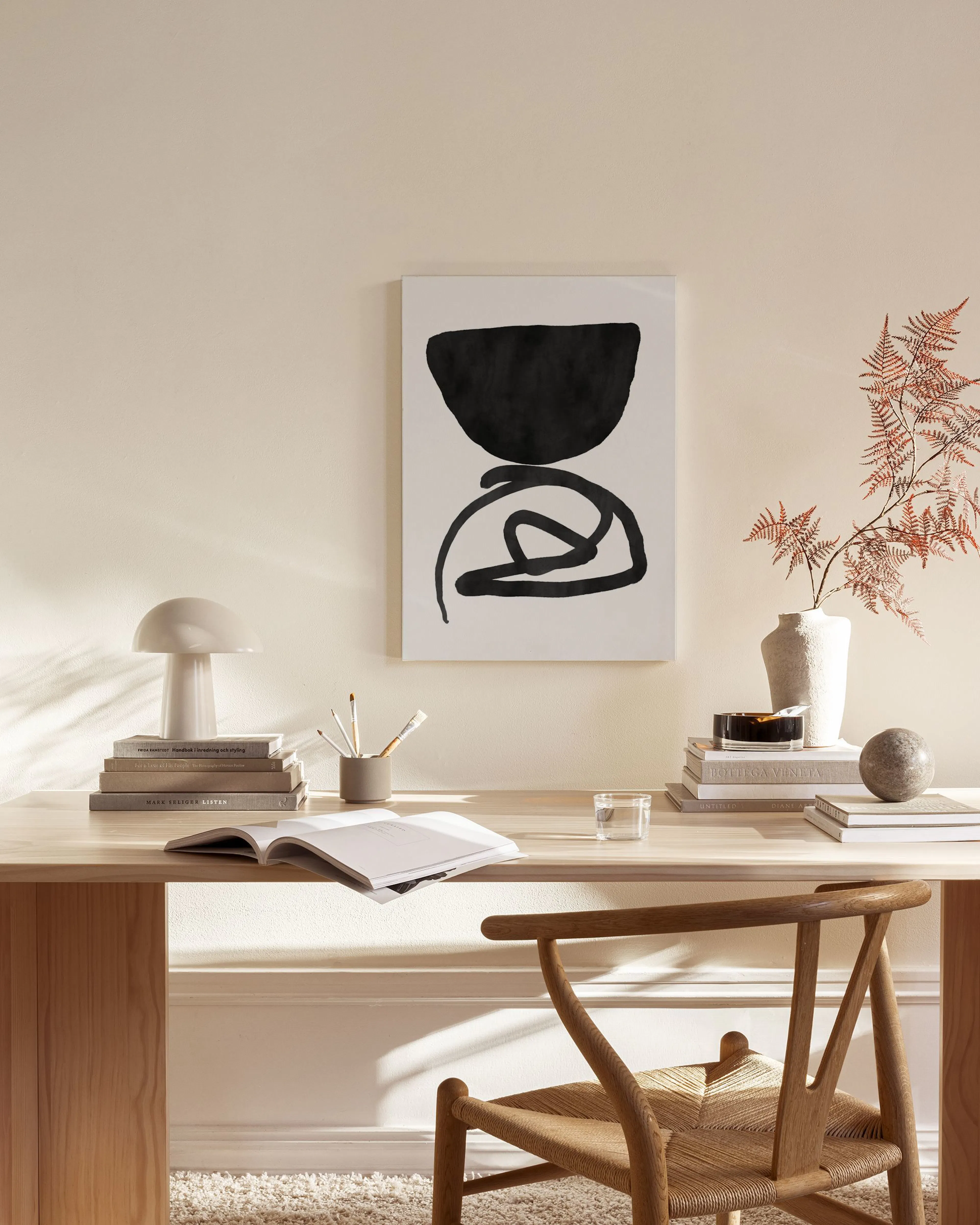 Abstract black shape resembling a bowl above a swirling black line, displayed in a minimal living room.