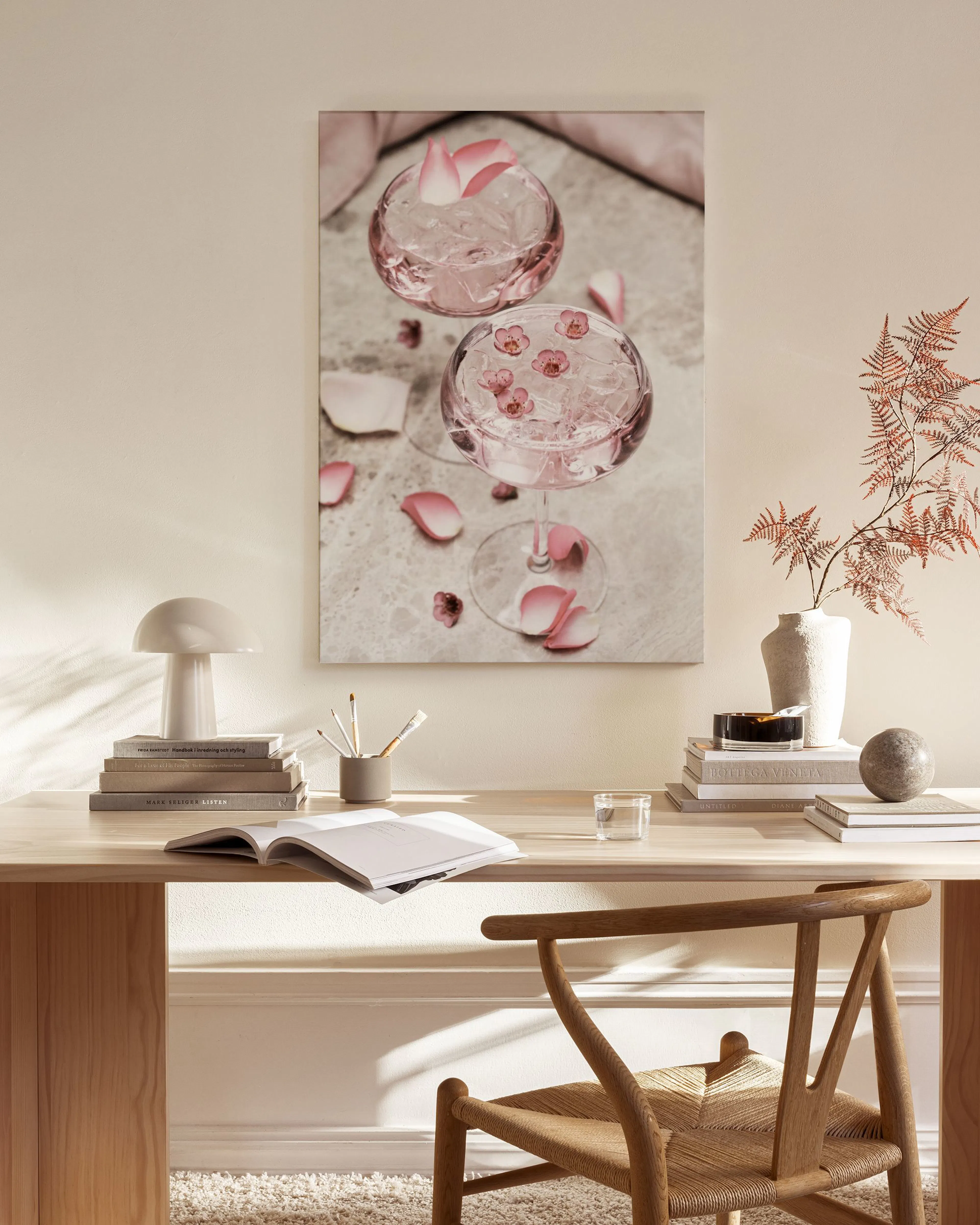 Leinwandbild mit zwei gefüllten Cocktailgläsern und rosa Blütenblättern, hängend über einem Sideboard im Wohnzimmer.