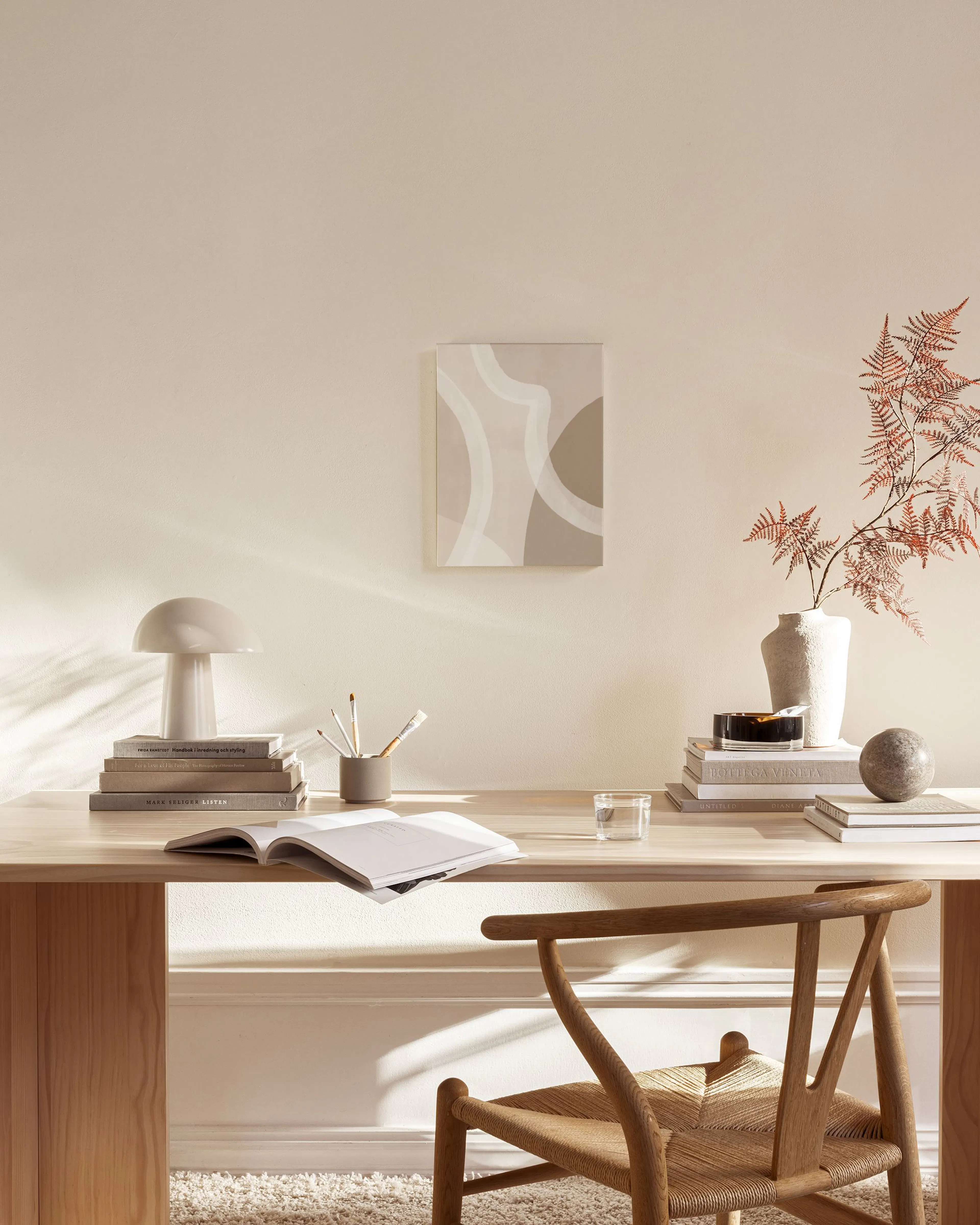 Abstract canvas print with curving beige and white shapes on a light brown background, displayed in a neutral-toned living room.
