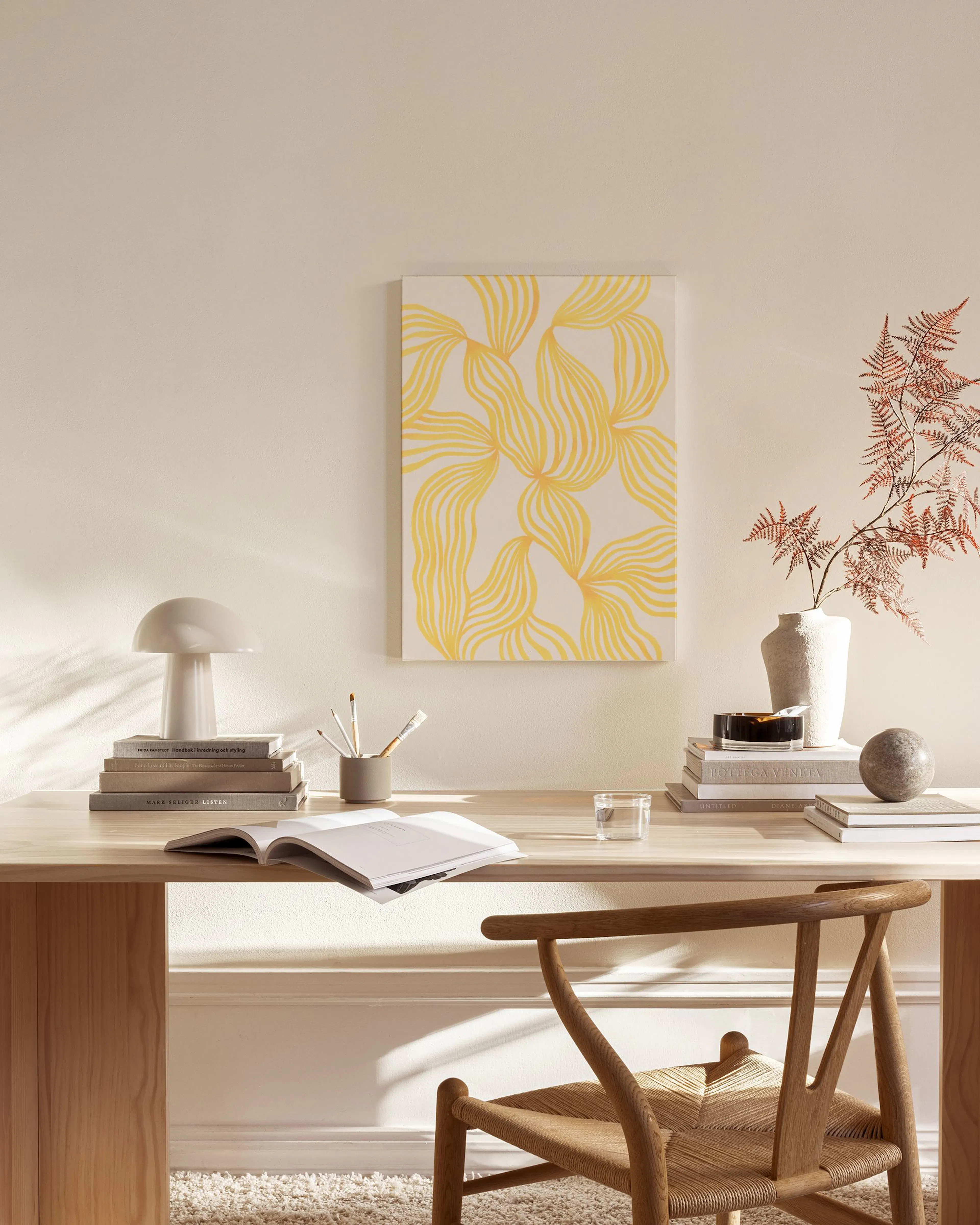 Toile aux motifs organiques jaunes sur fond clair, suspendue dans un salon moderne aux tons neutres.