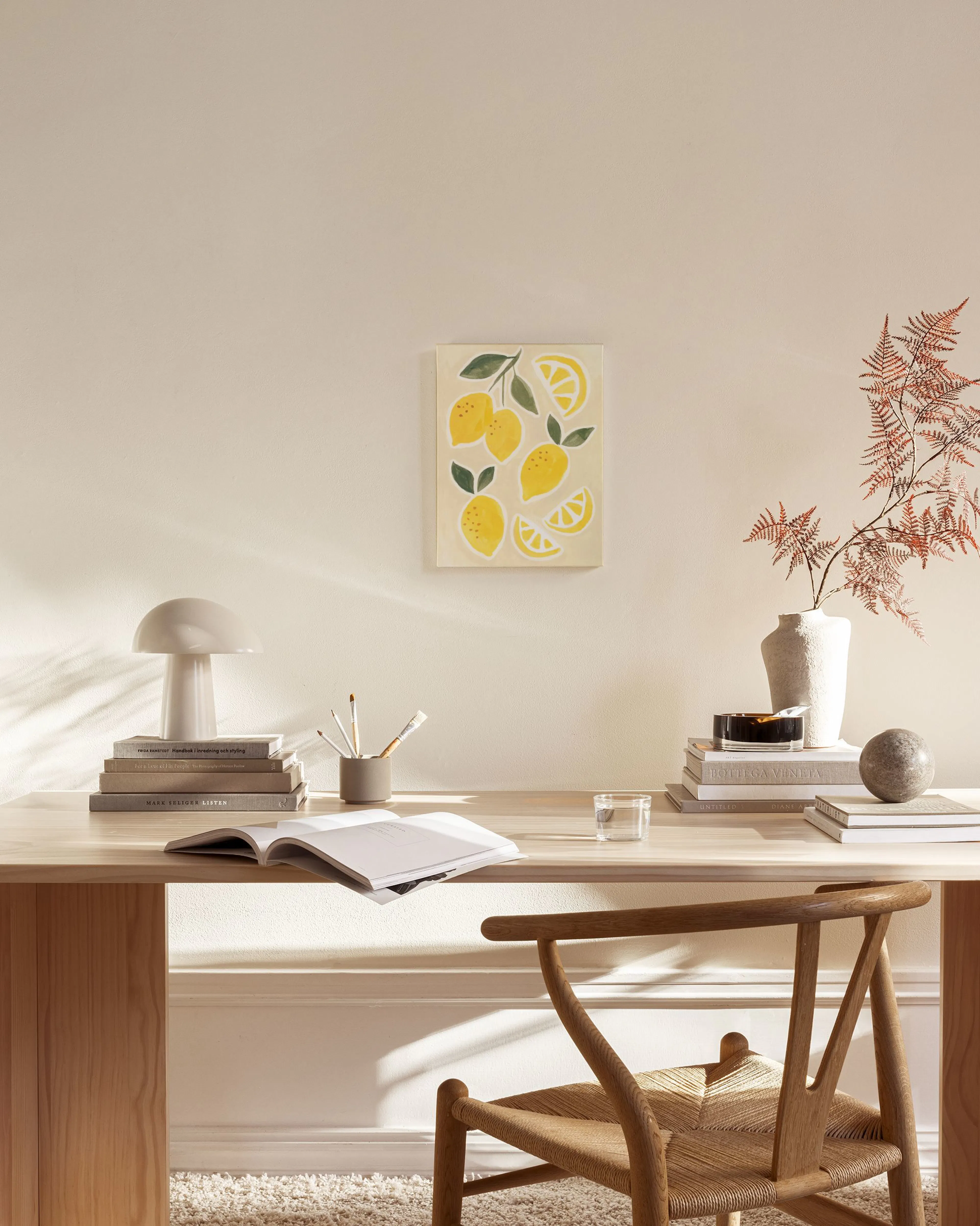 Leinwandbild mit gelben Zitronen und grünen Blättern, hängend in einem hellen Wohnzimmer über einem Sideboard.