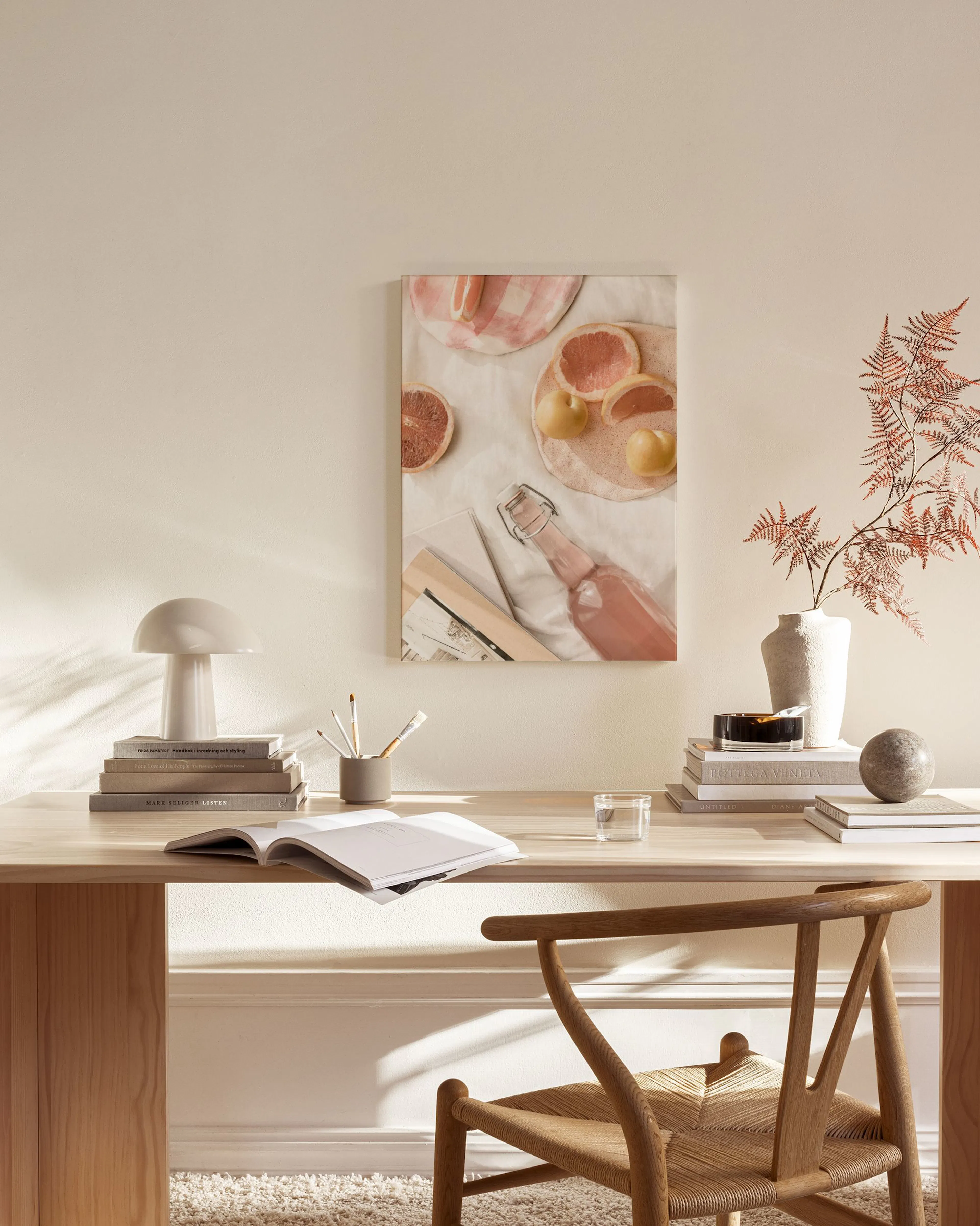 Toile murale, composition de pamplemousses et citron sur assiettes en céramique, avec une bouteille rose, dans un salon moderne.