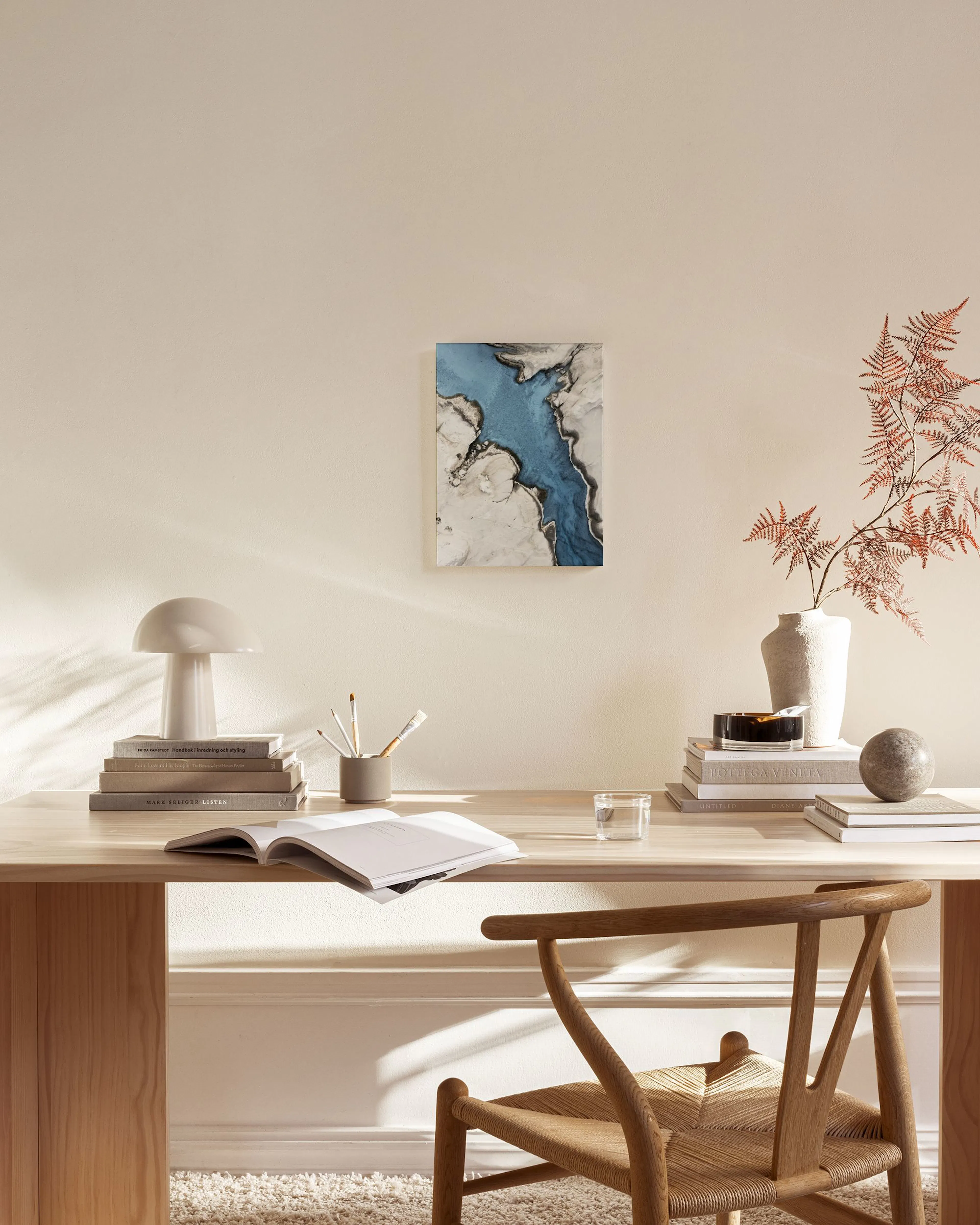Abstraktes Leinwandbild in Blau, Grau und Beige, an einer hellen Wand in einem modernen Wohnzimmer.