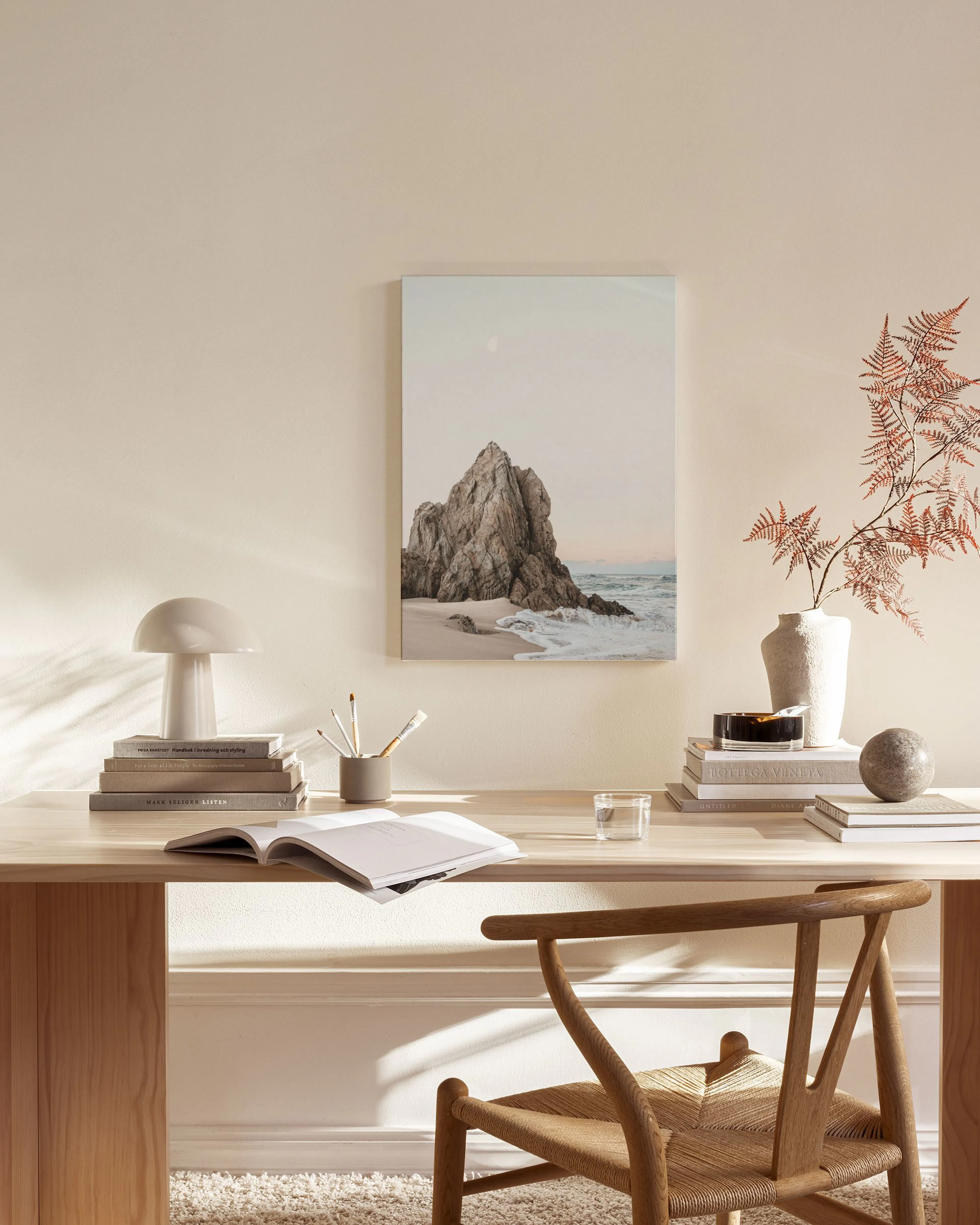 Leinwandbild einer Felsformation am Meer mit Wellen und einem Himmelskörper, hängt in einem modernen Wohnzimmer über einem Sideb