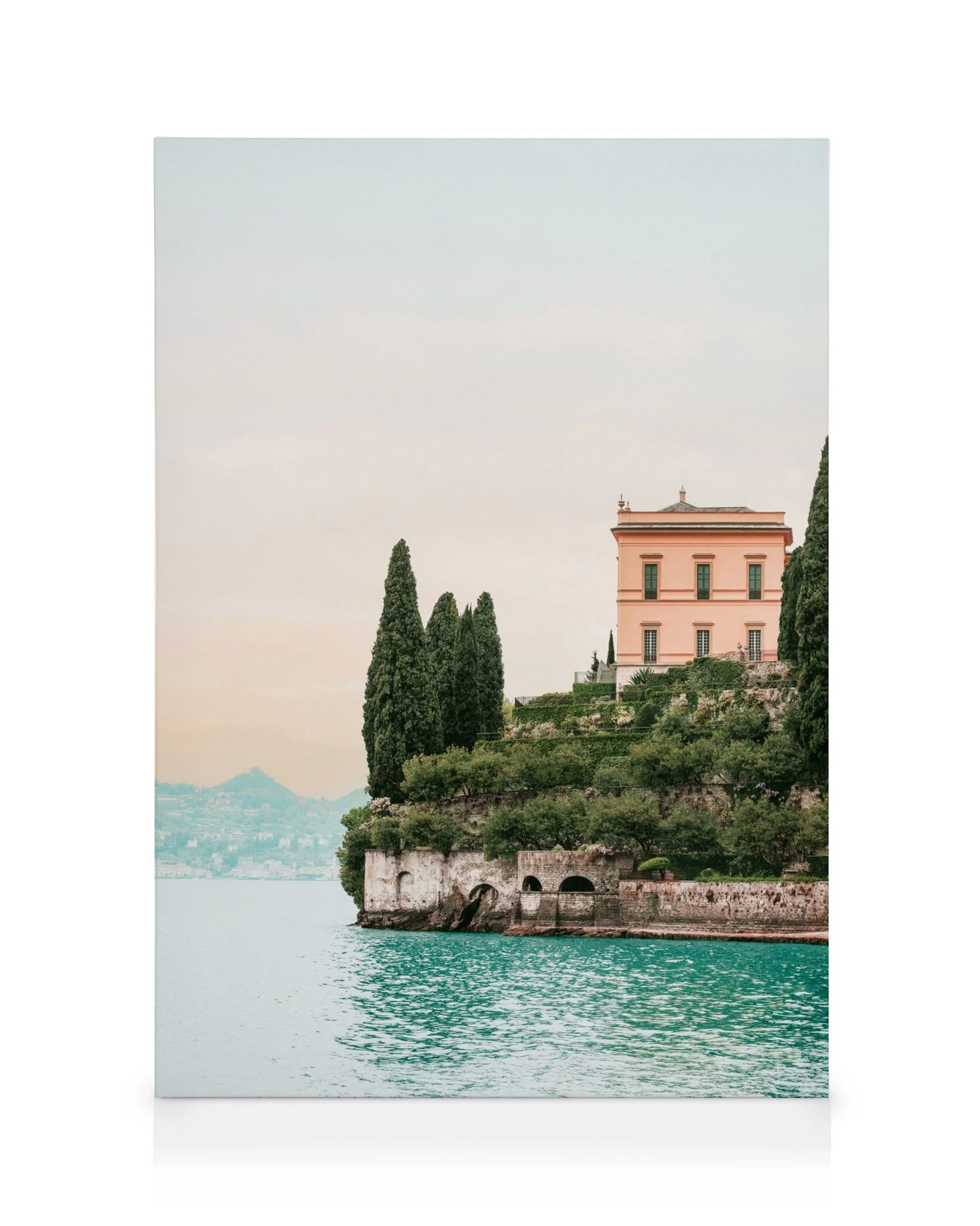 Lienzo Villa Cipressi: Casa rosa sobre un acantilado verde con cipreses, frente a aguas azules y cielo pálido.