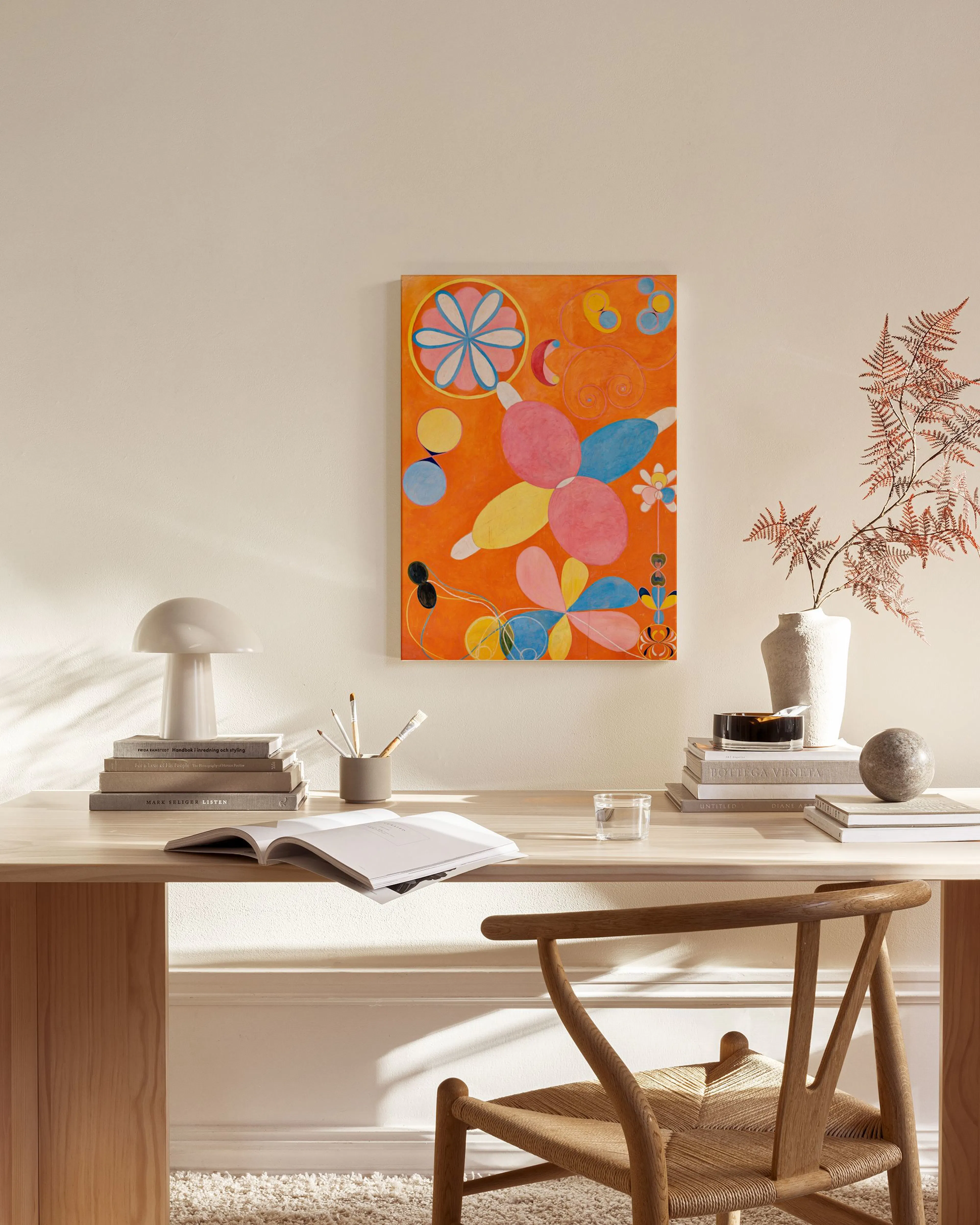 Abstract canvas print with colourful organic shapes on an orange background, hanging in a modern living room.
