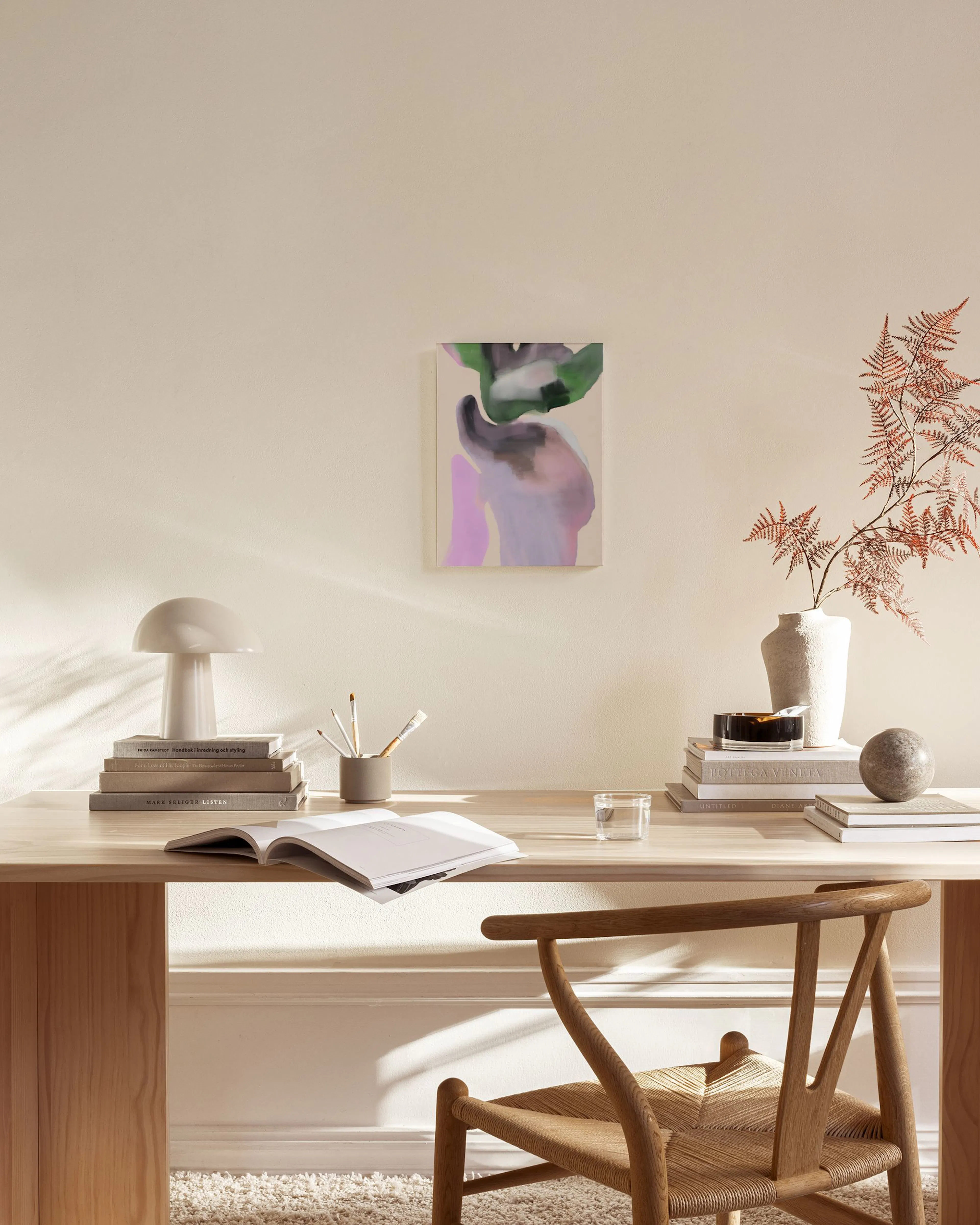 Abstract canvas print with organic shapes in green, lilac, and grey tones, hanging above a timber credenza in a living room.