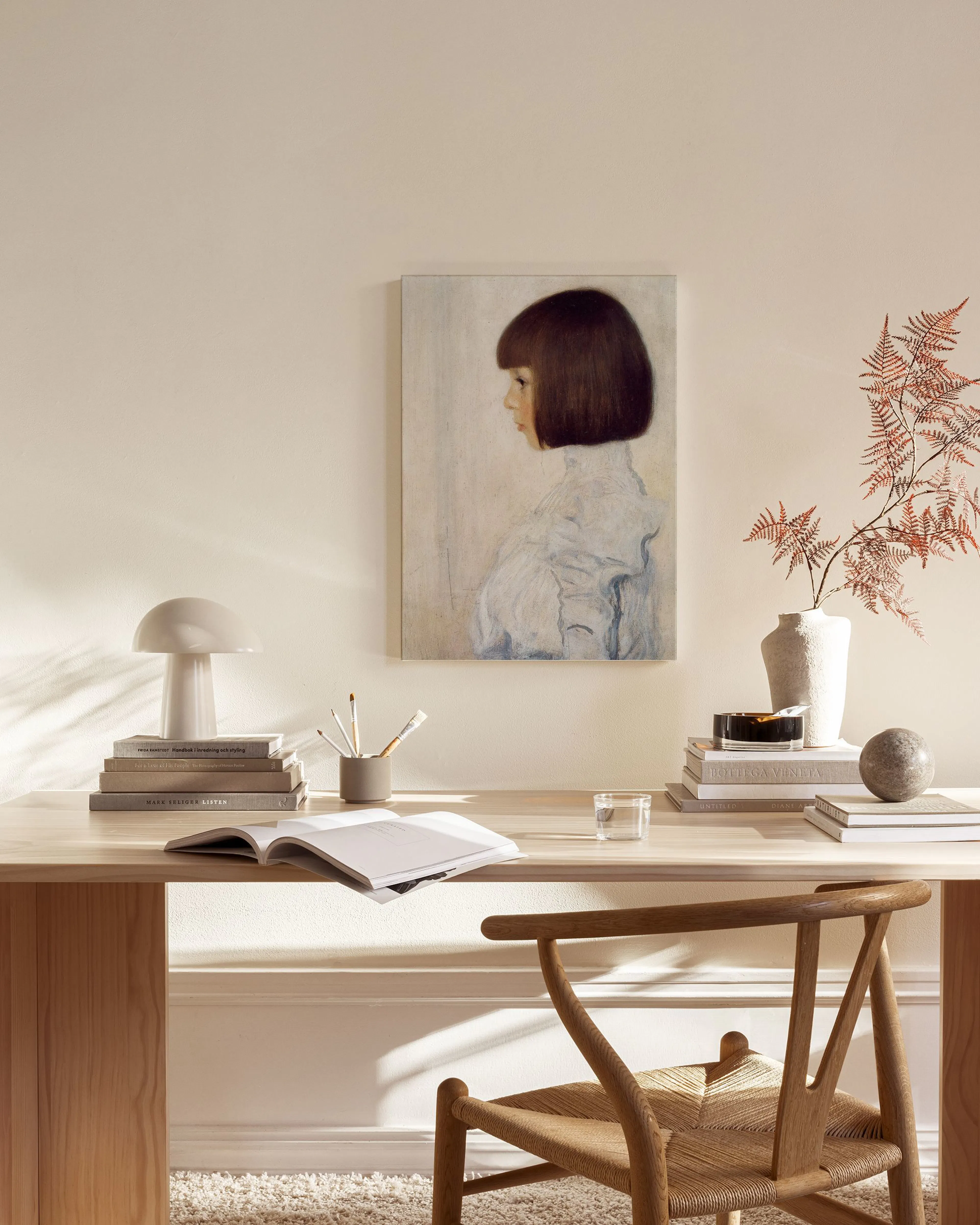 Portrait of a girl with dark bobbed hair in profile, hanging in a minimalist living room above a wooden console.