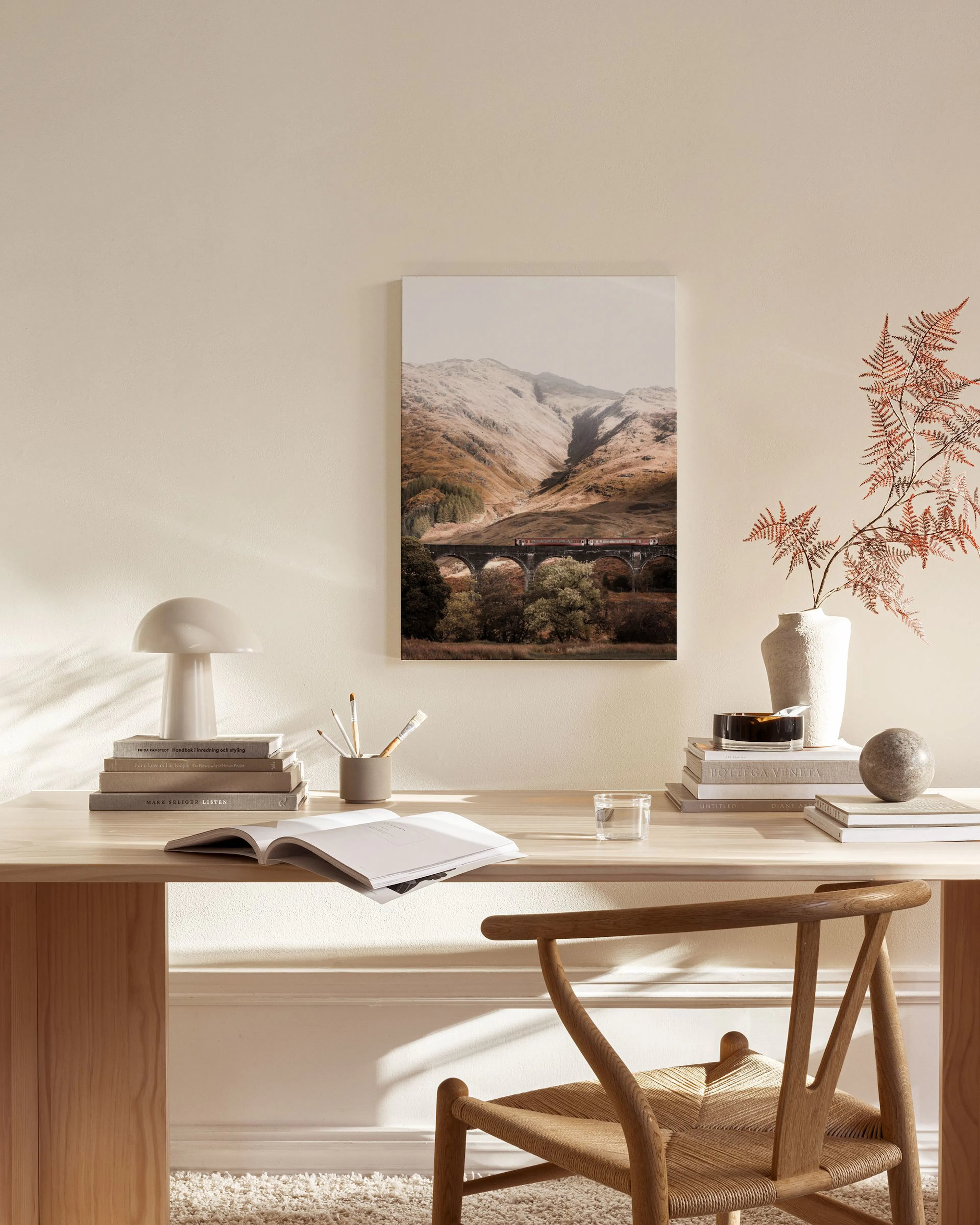 Toile murale paysage montagneux avec viaduc et train, affichée dans un salon moderne aux tons neutres.