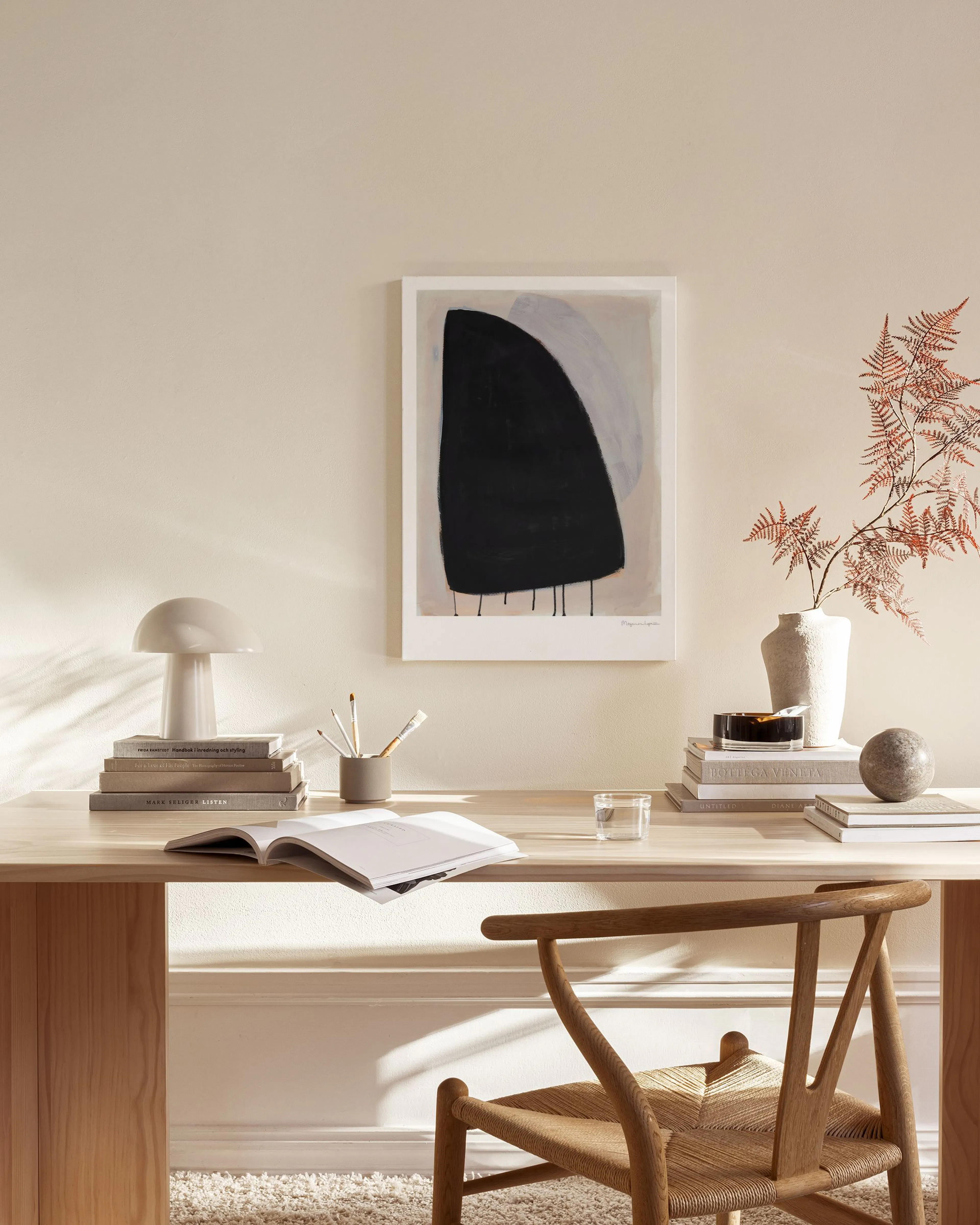 Toile abstraite noir et gris clair sur fond beige, suspendue dans un salon moderne au-dessus dun banc en bois.
