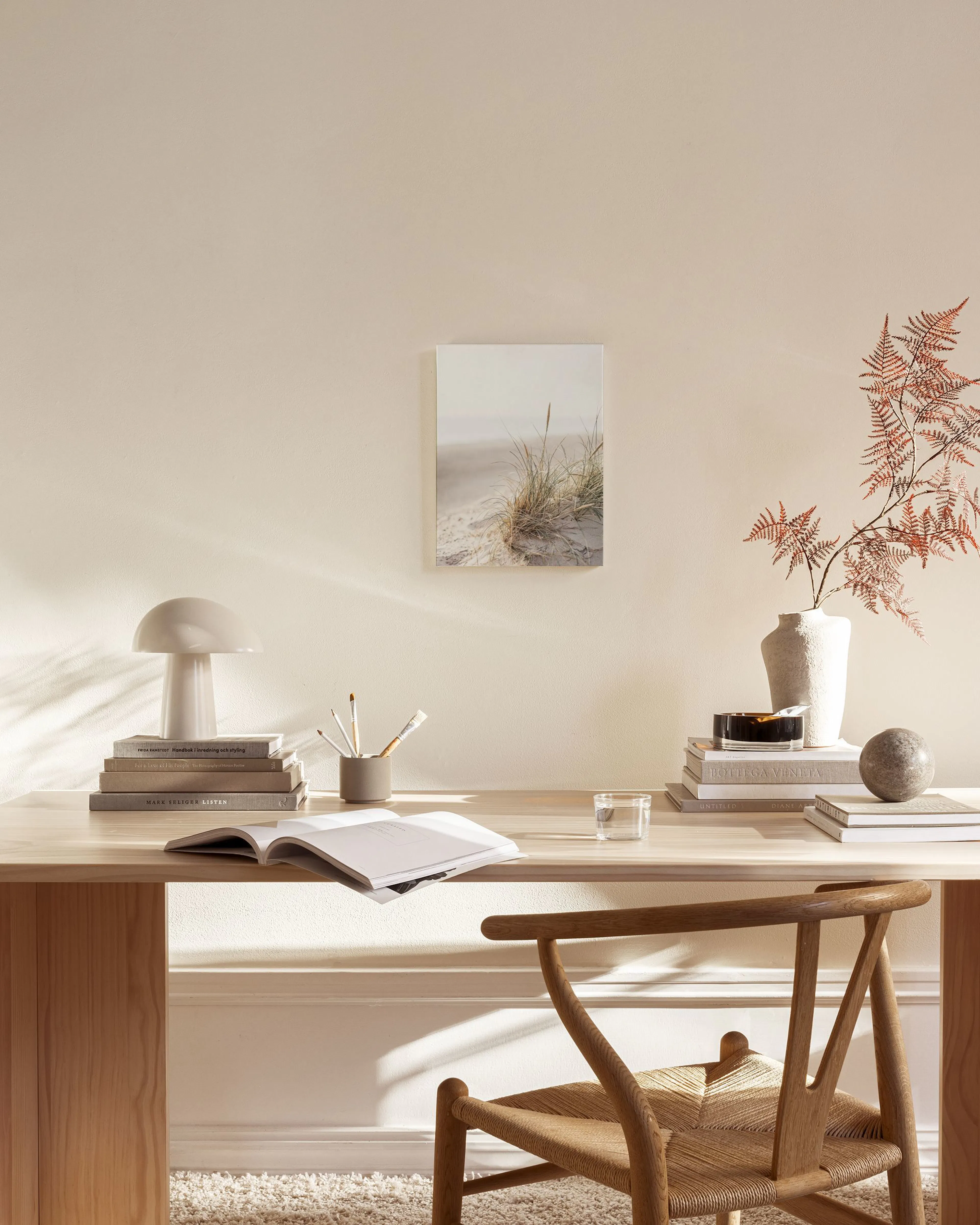 Lienzo de un paisaje de dunas de arena con hierba de playa, colgado en una sala de estar moderna con muebles de madera.