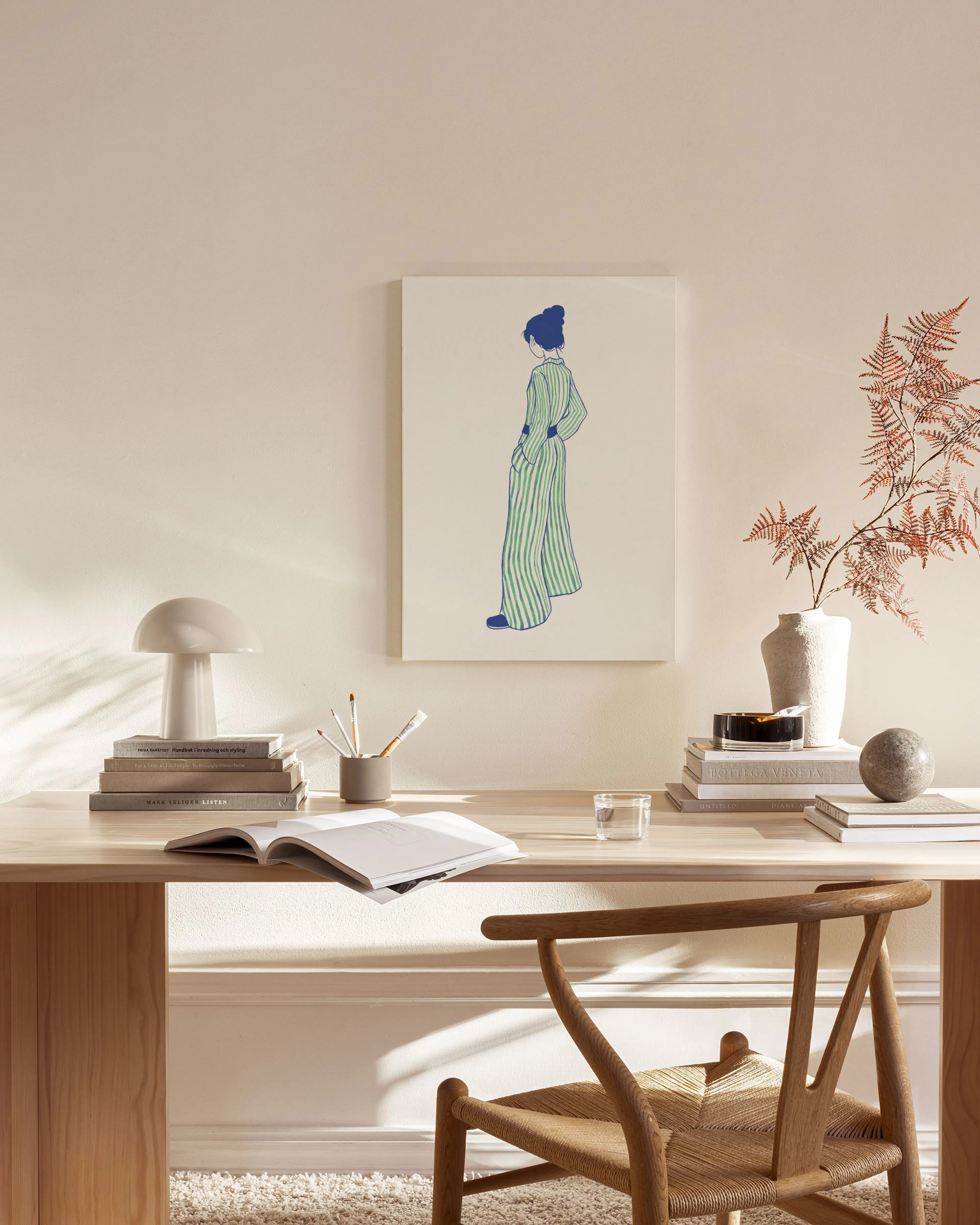Canvastavla med illustration av kvinna i randiga kläder på ljus bakgrund, hängande i ett ljust vardagsrum.