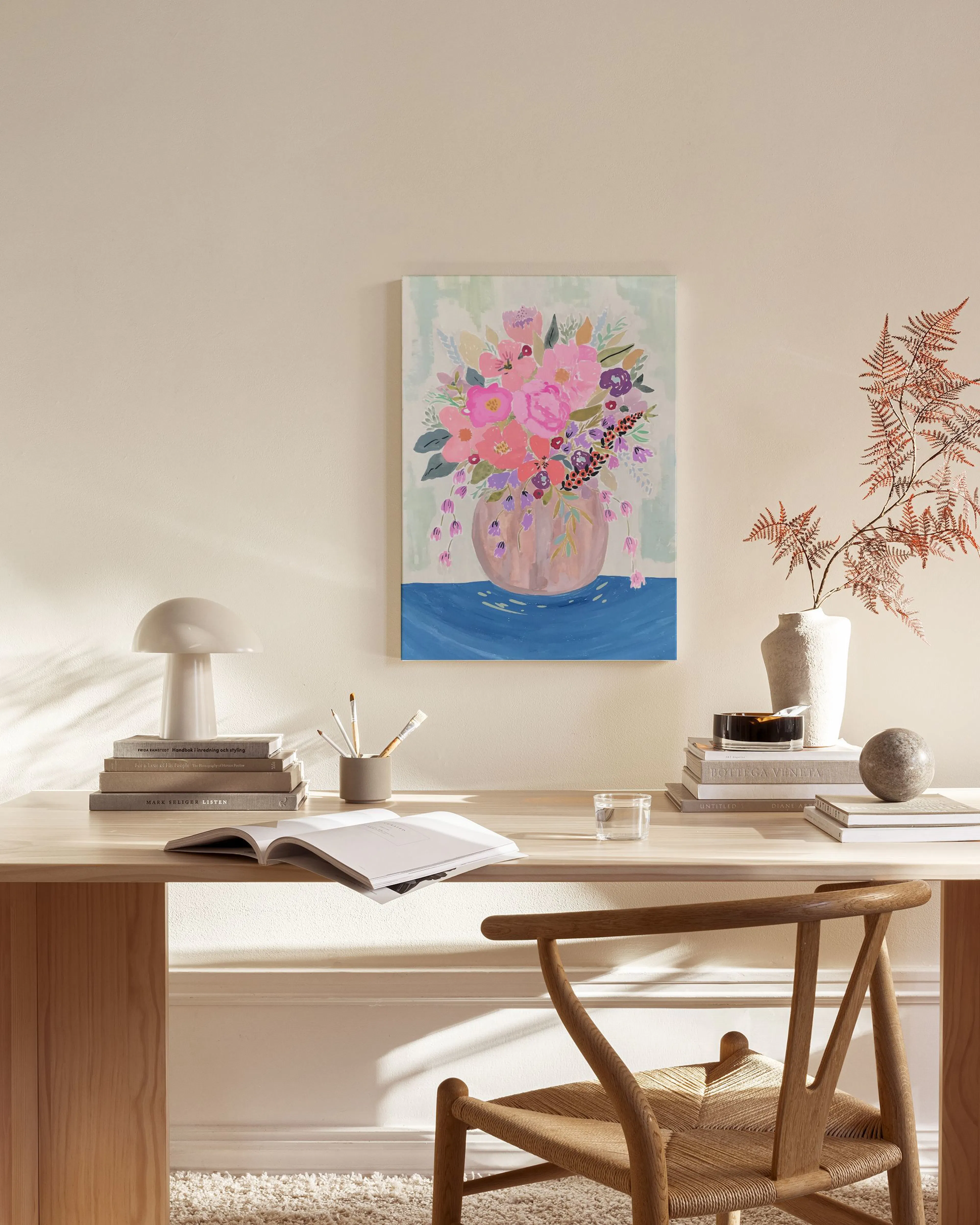 Een canvas met een kleurrijk boeket roze en paarse bloemen in een vaas, hangend in een eigentijdse woonkamer.