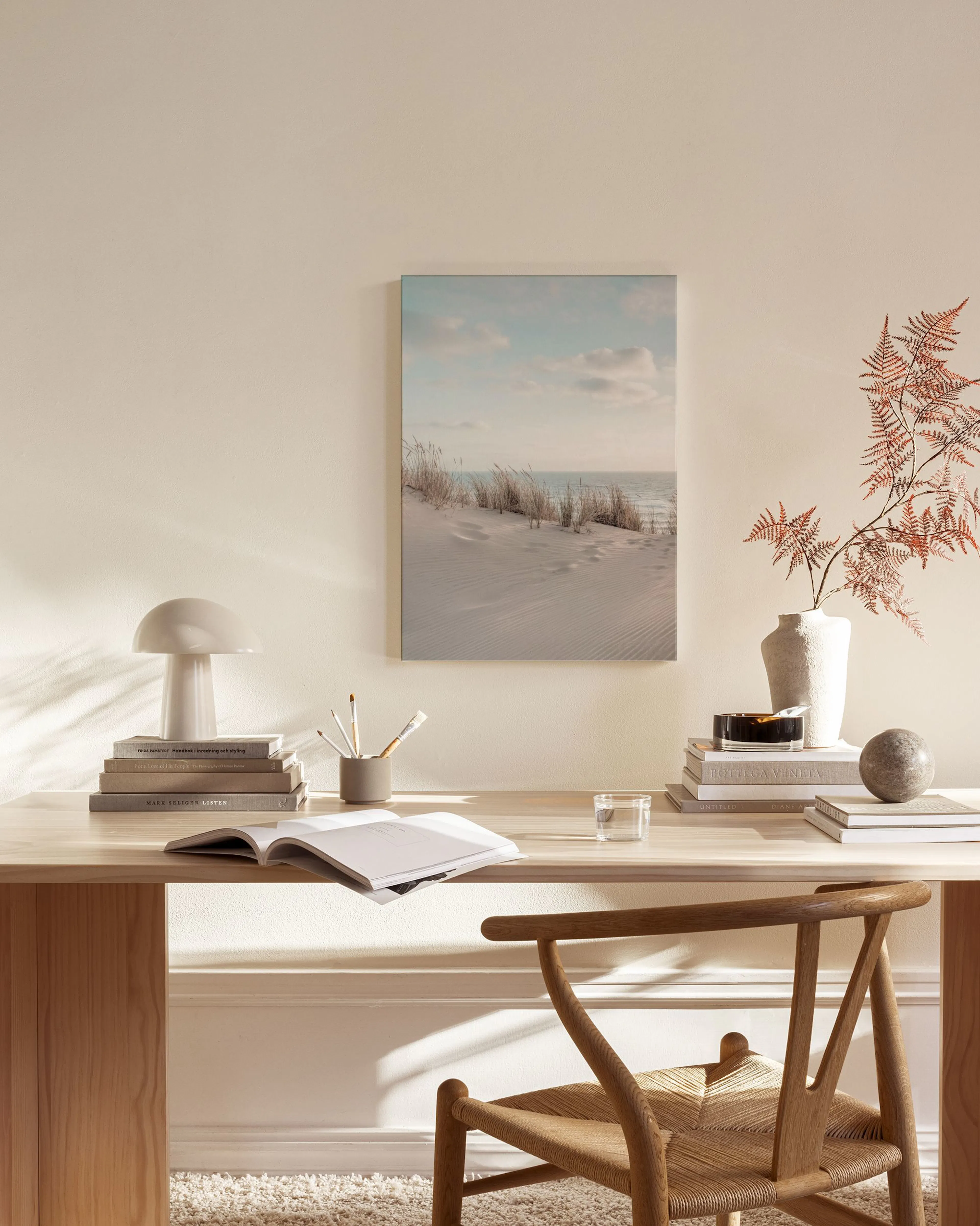 Toile murale de dunes de sable et herbes sèches sous un ciel nuageux, suspendue dans un salon moderne.
