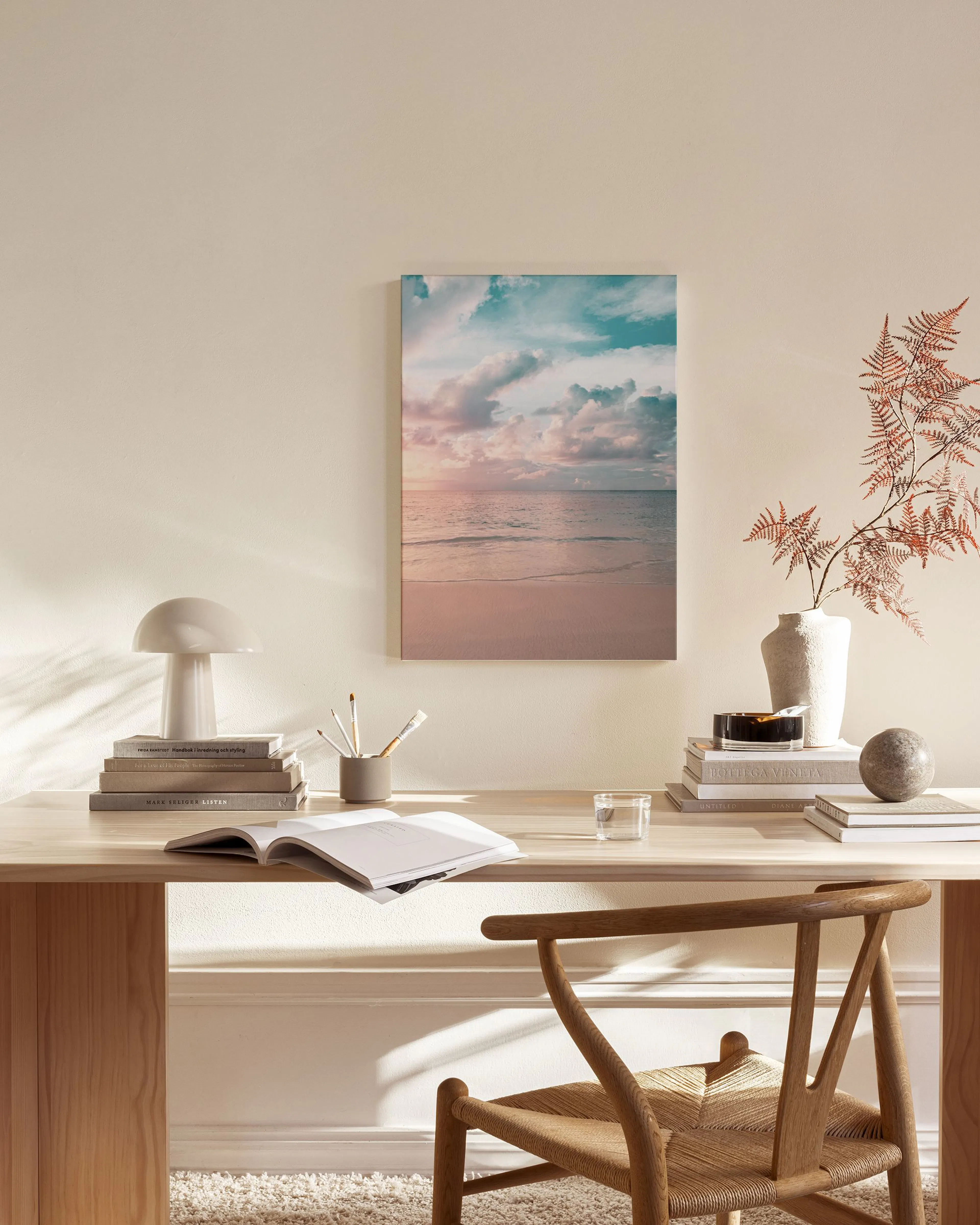 Leinwandbild eines Sonnenuntergangs am Meer mit rosa Sand und türkisfarbenem Himmel, hängend in einem modernen Wohnzimmer über e