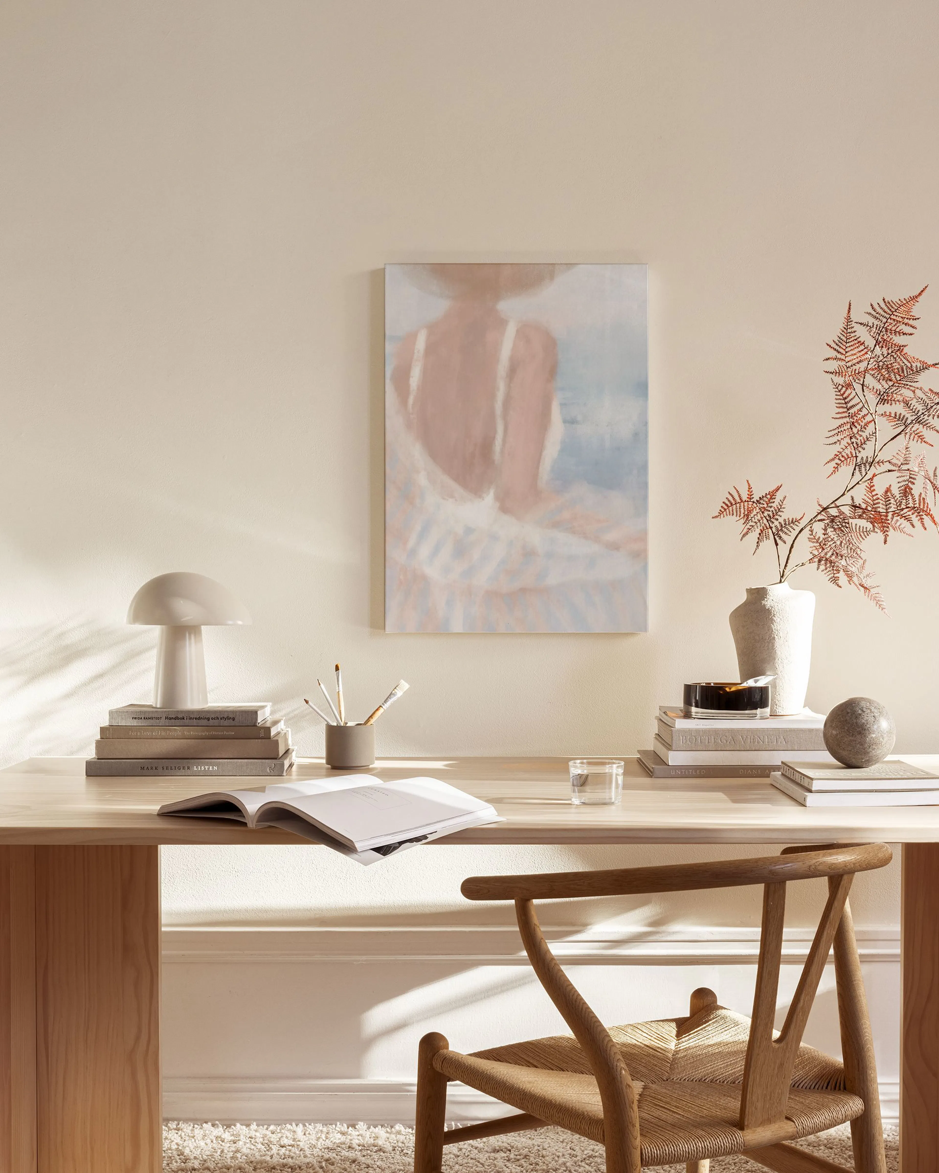Leinwandbild einer Frau mit Hut von hinten, in einem modernen, hellen Wohnzimmer über einem Sideboard.