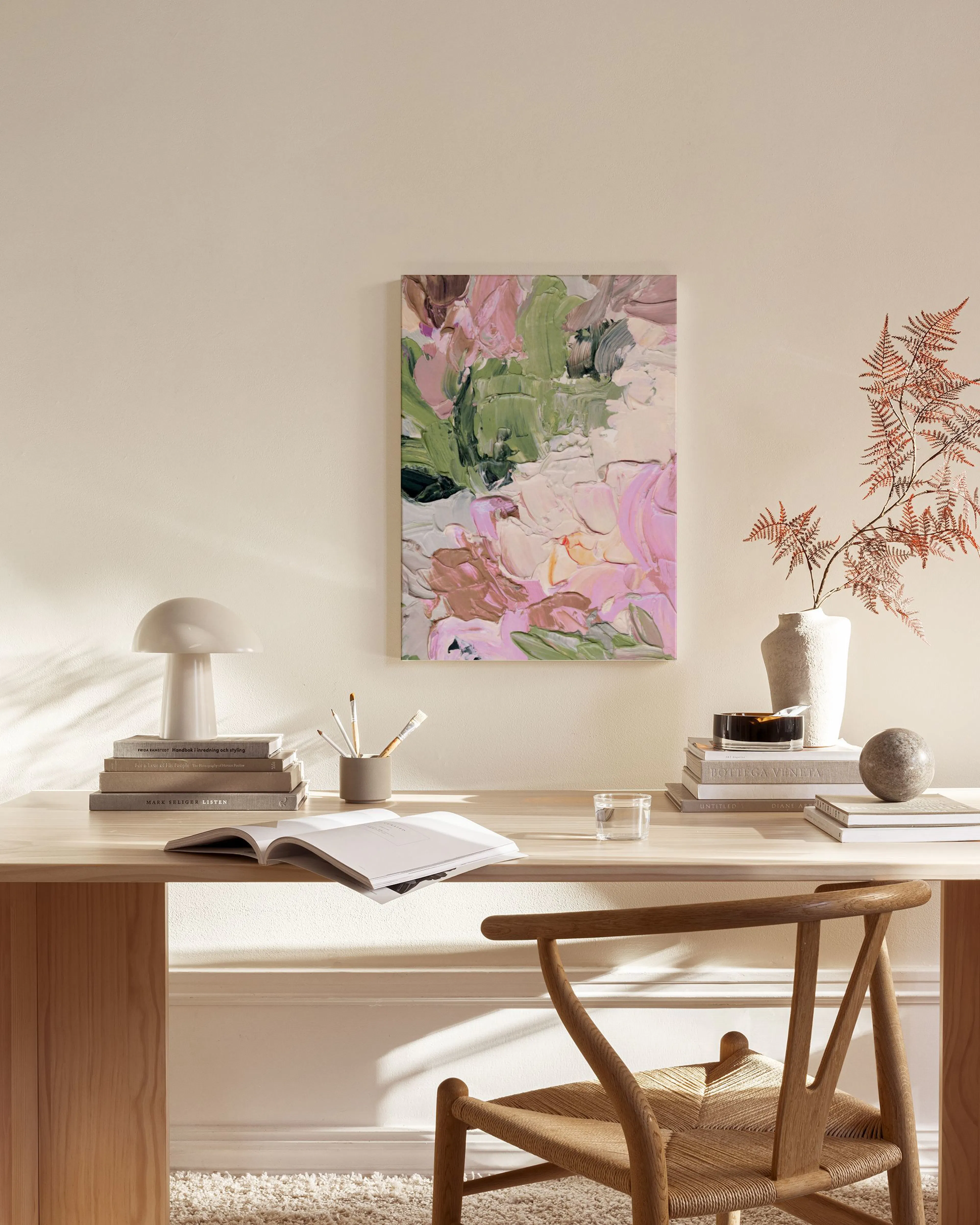 Toile abstraite aux formes épaisses roses, vertes et blanches, accentuant un salon moderne avec fauteuil en bois clair.
