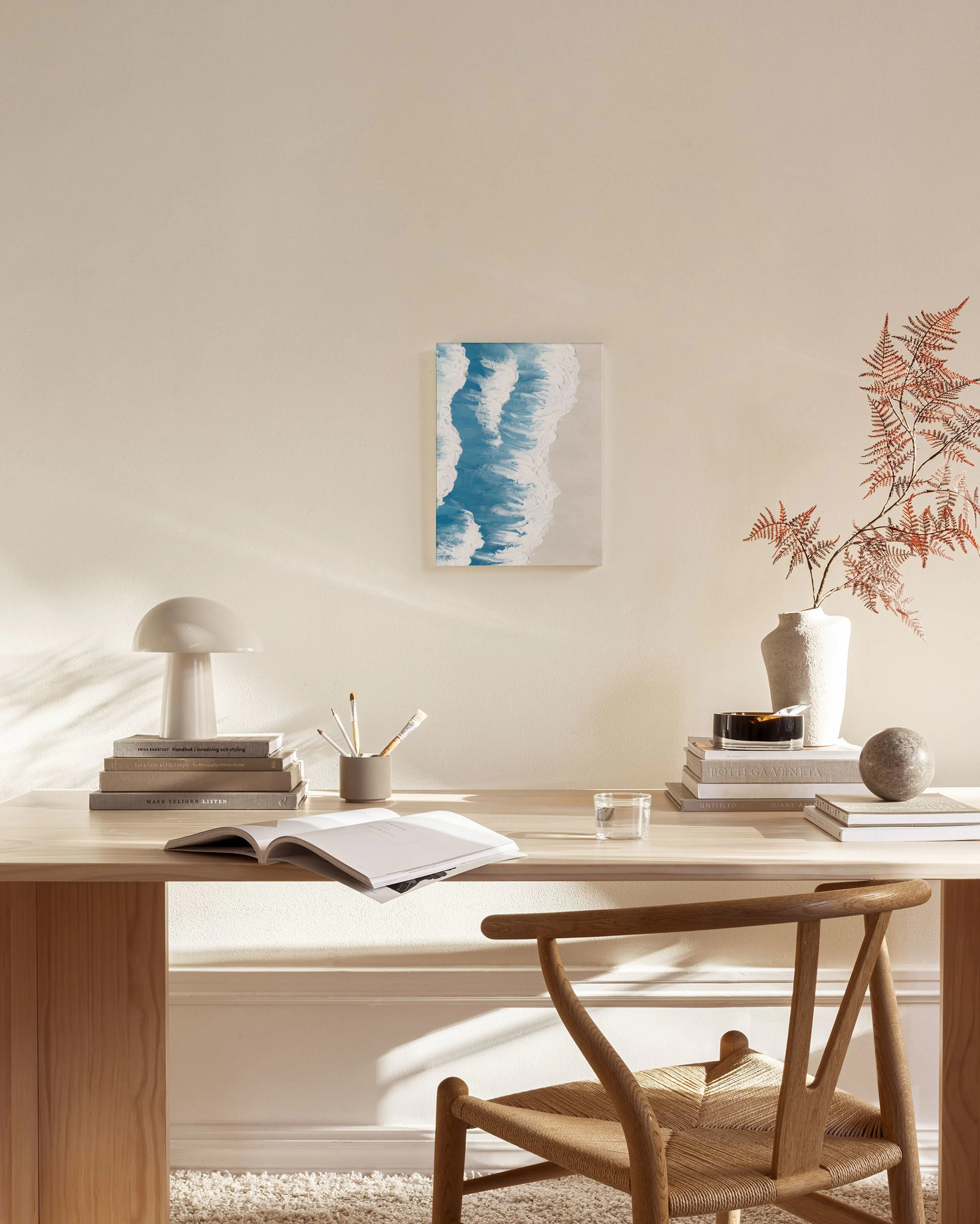 Leinwandbild mit Meereswellen in Blau und Weiß, an einer hellen Wand über einem Sideboard im Wohnzimmer.