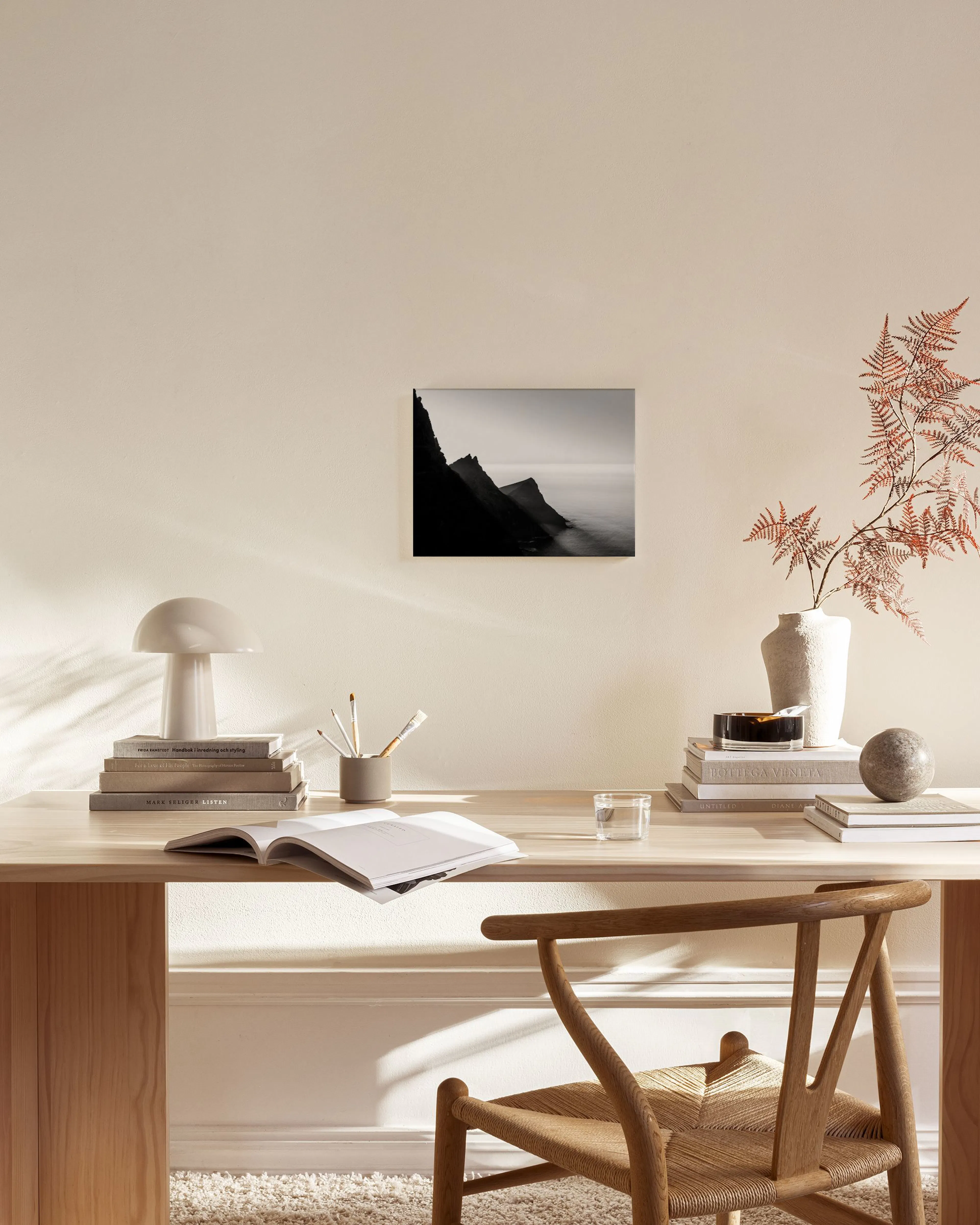 Leinwandbild mit schwarz-weißer Küstenlandschaft, hängend in einem minimalistischen Wohnzimmer über einem Sideboard.
