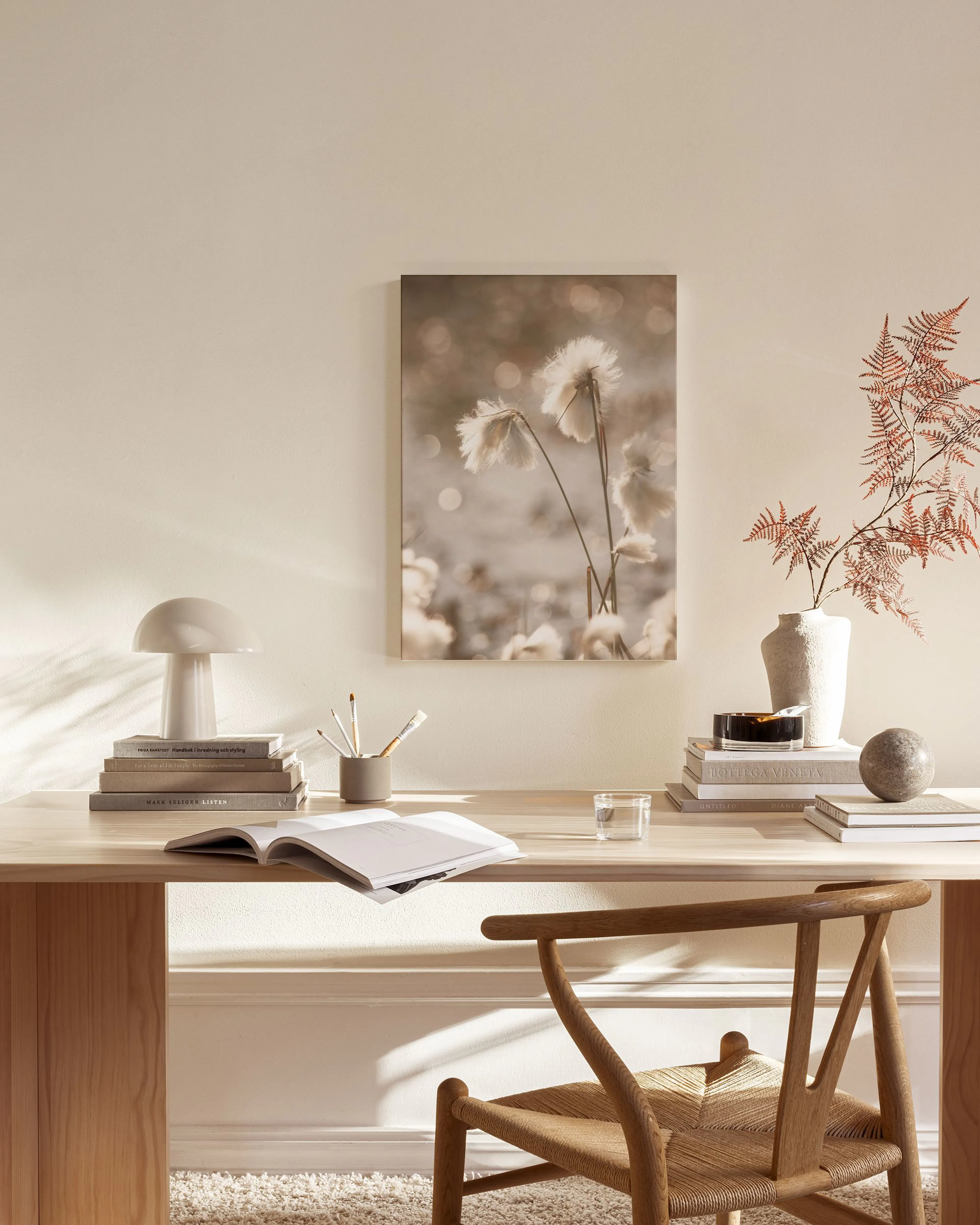 Toile florale aux tons neutres, représentant des fleurs blanches duveteuses, suspendue dans un salon scandinave.
