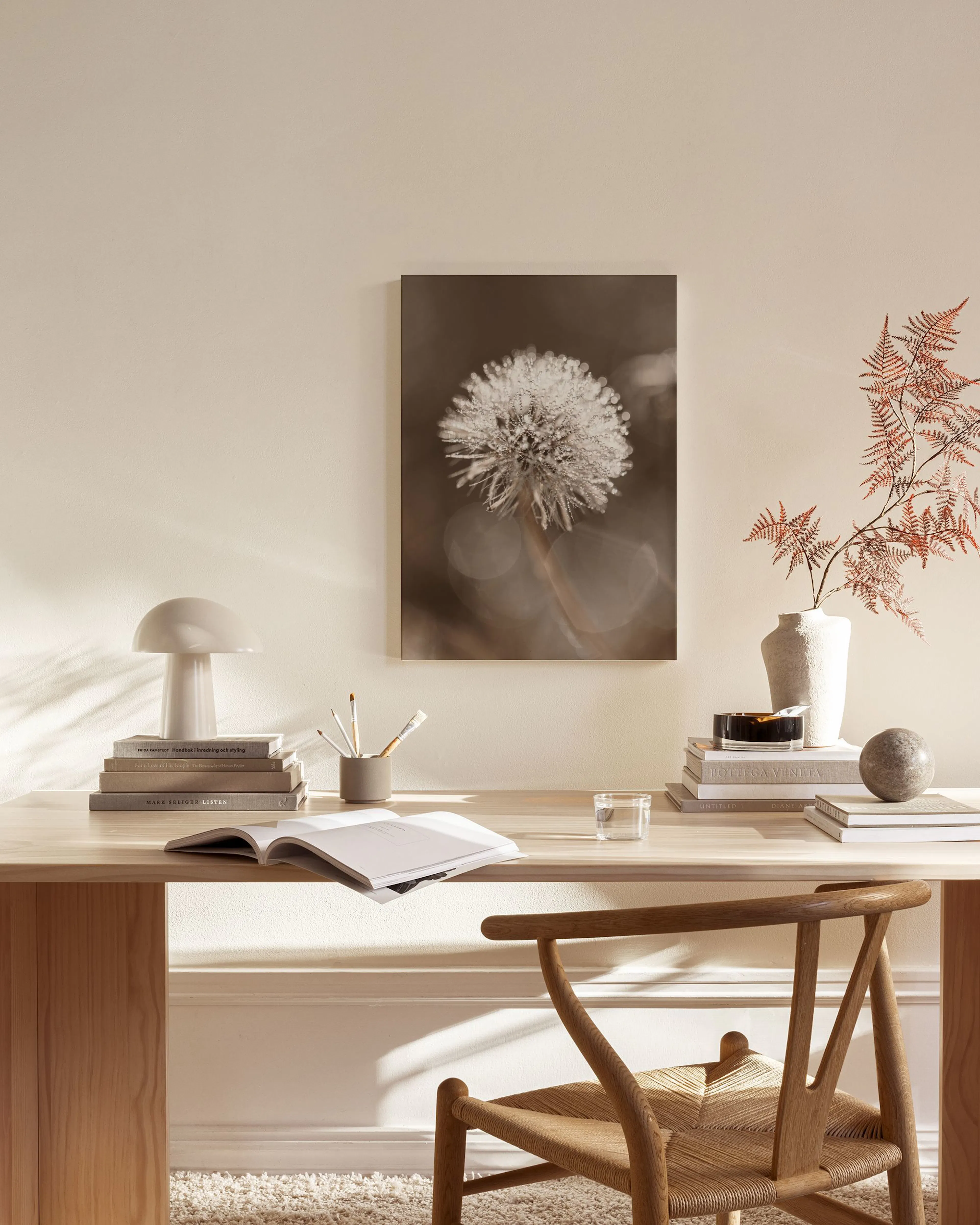 A canvas print of a dandelion with frost on its seeds, displayed in a minimal living room.