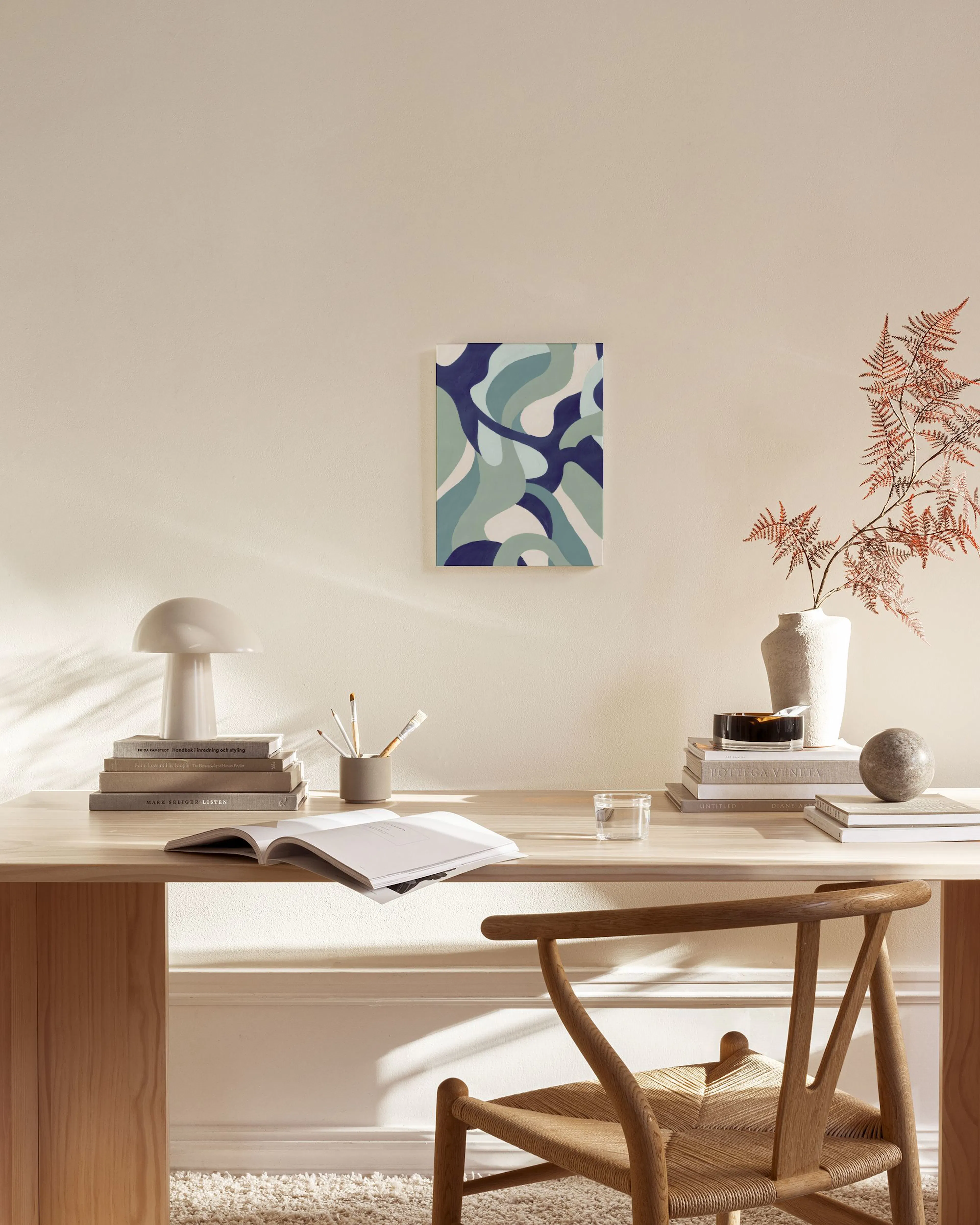 Toile aux formes organiques bleues, aqua et blanches, suspendue au-dessus dun banc en bois clair dans un salon moderne.
