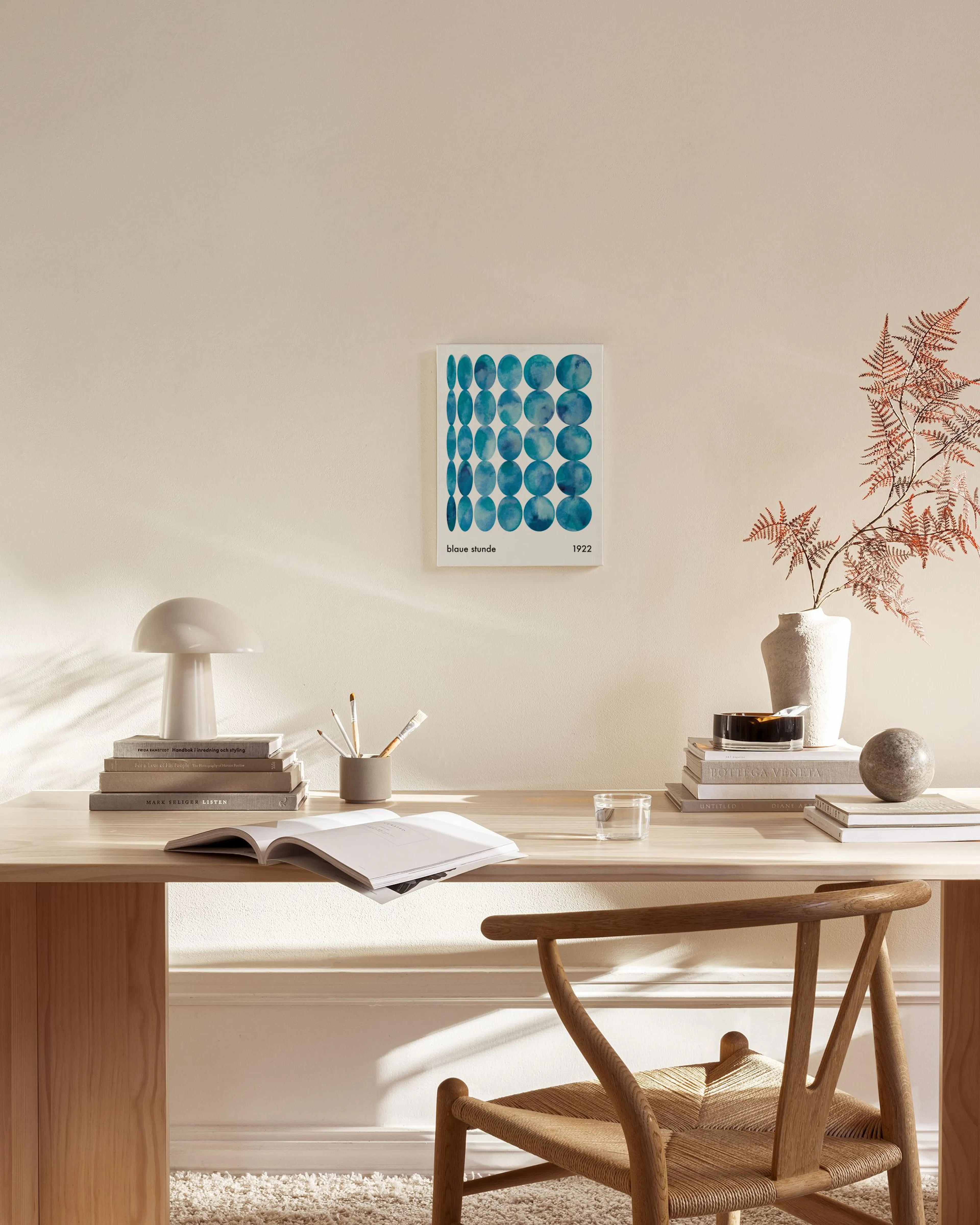 Toile de cercles bleus aquarellés, suspendue dans un salon moderne avec fauteuil en bois et table basse.