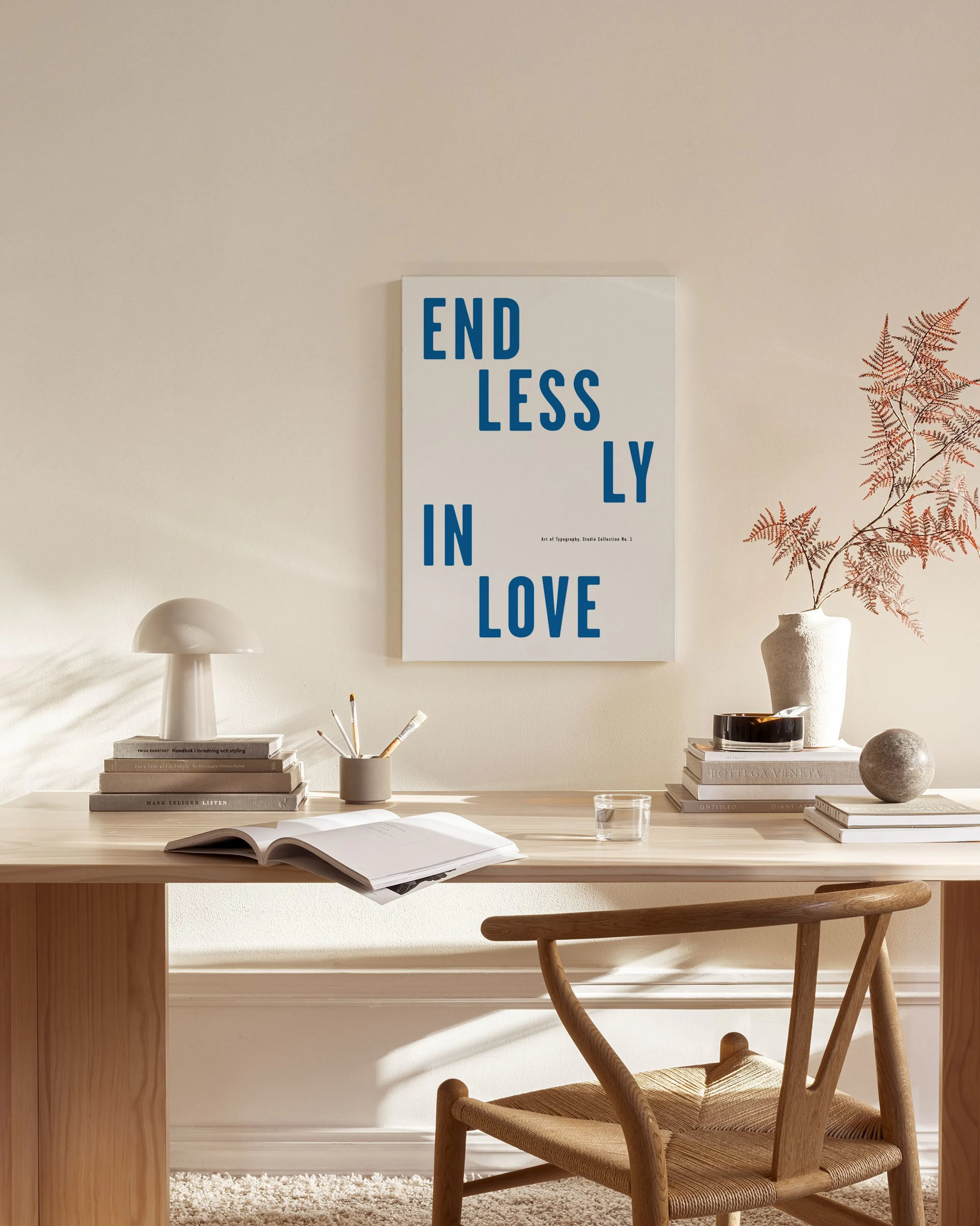Canvas met blauwe tekst ENDLESSLY IN LOVE op witte achtergrond, hangend in een neutrale woonkamer boven een houten dressoir.