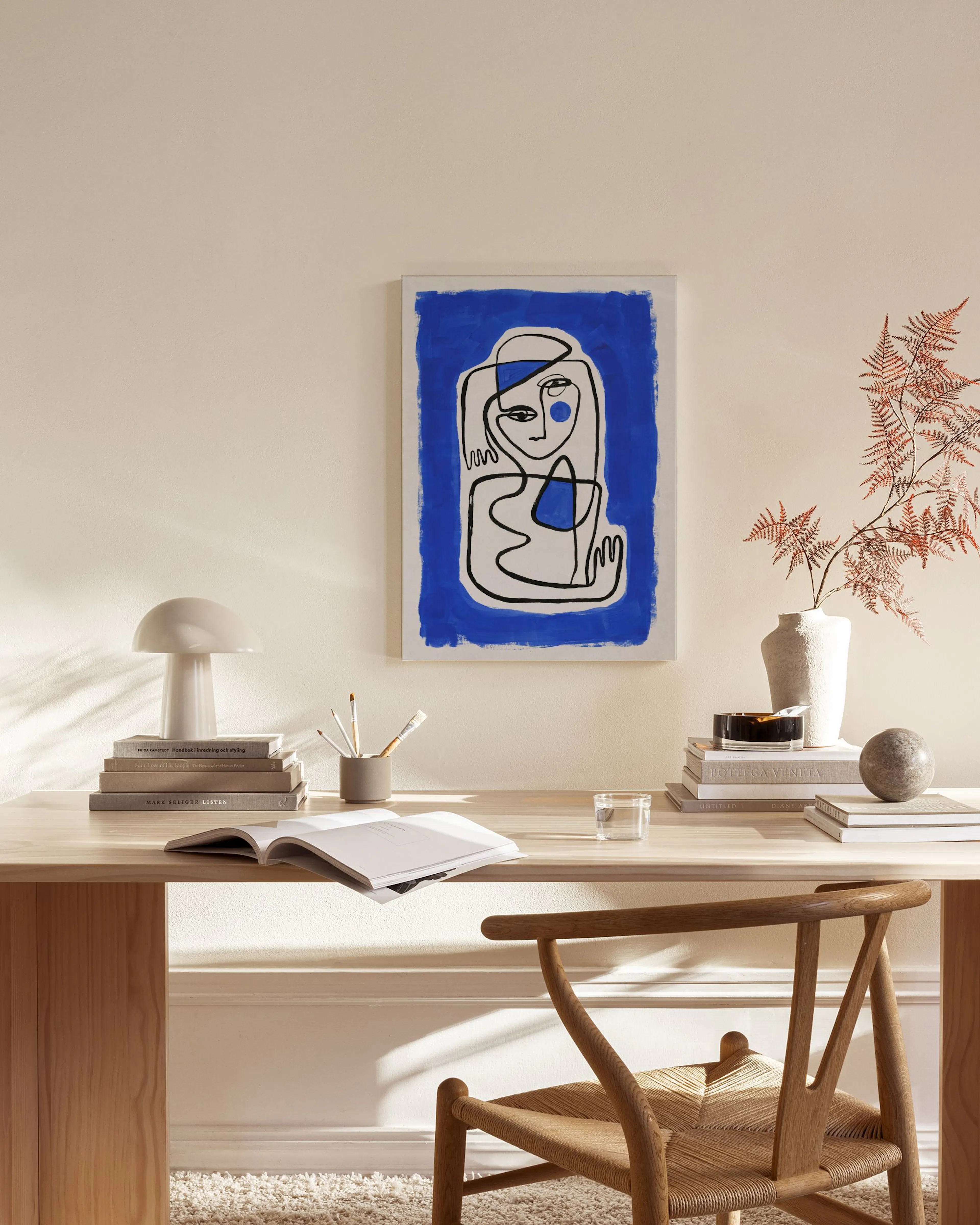 Toile murale abstraite en bleu vif avec des formes organiques noires et blanches, accrochée dans un salon moderne.