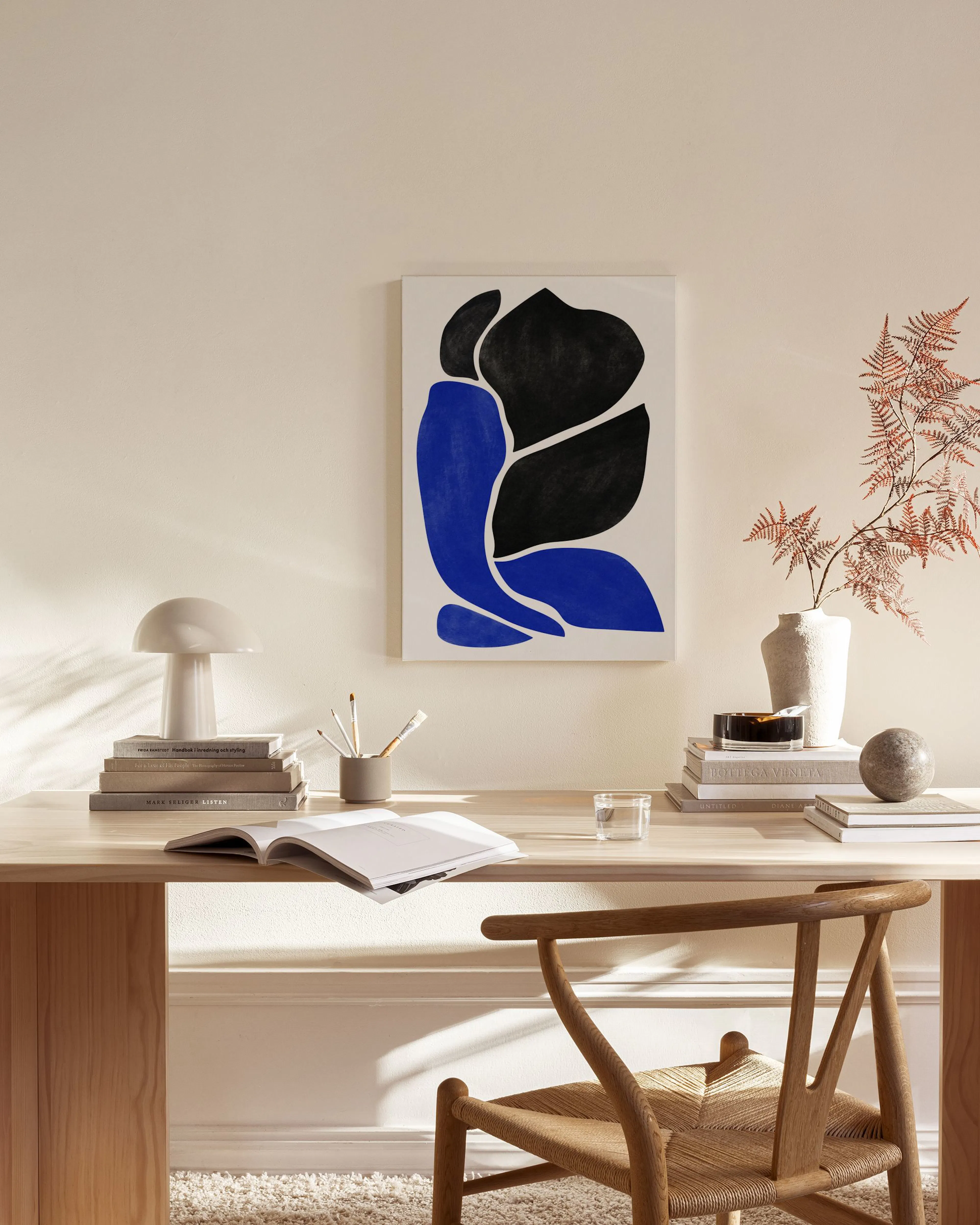 Abstract canvas print with black and blue organic shapes on a white background, hanging in a modern living room.