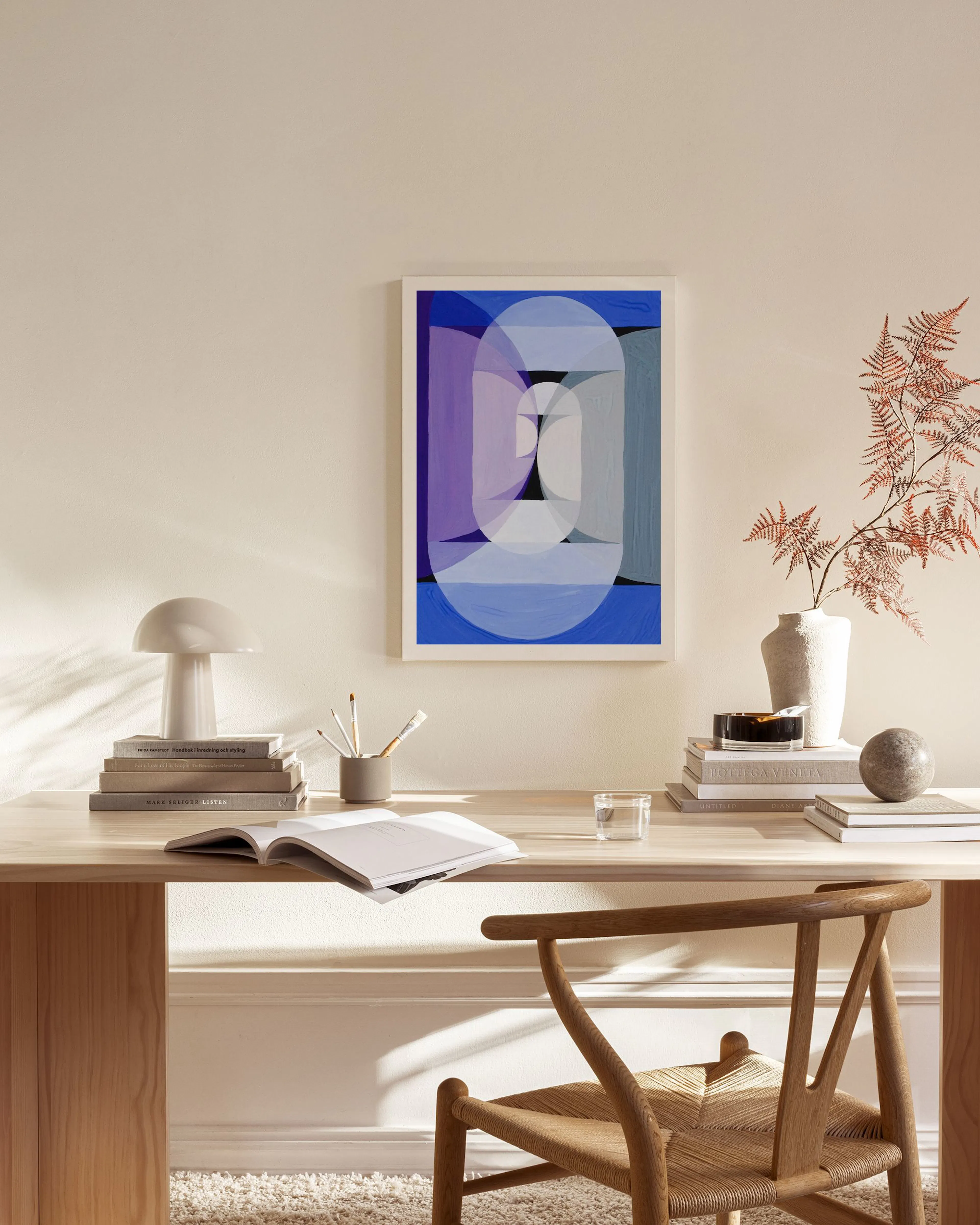 Abstract canvas print of stacked blue and purple geometric shapes, hanging in a minimalist living room.