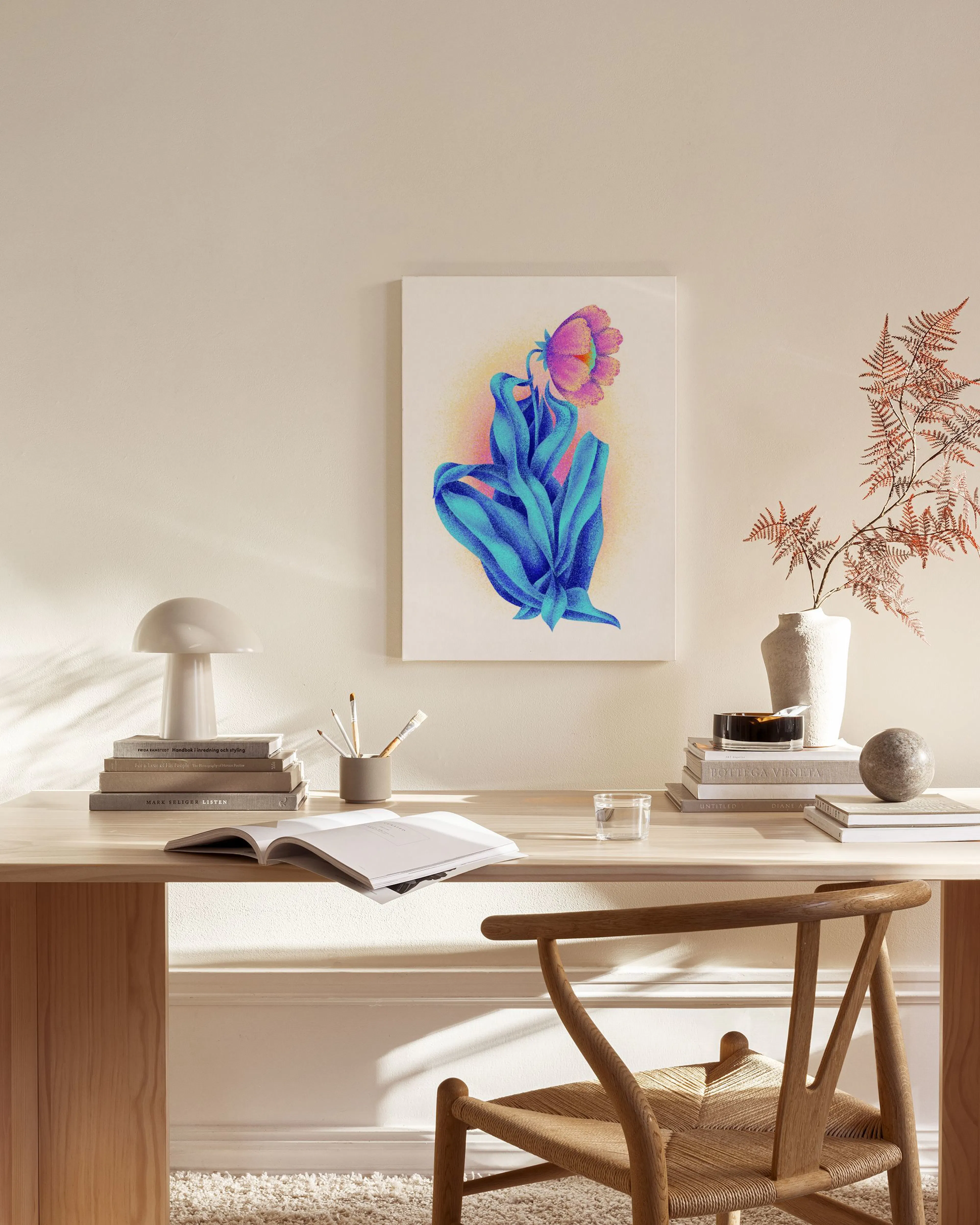 A canvas print of a figure with blue legs and a pink flower head, hanging above a wooden console table in a minimalist living ro