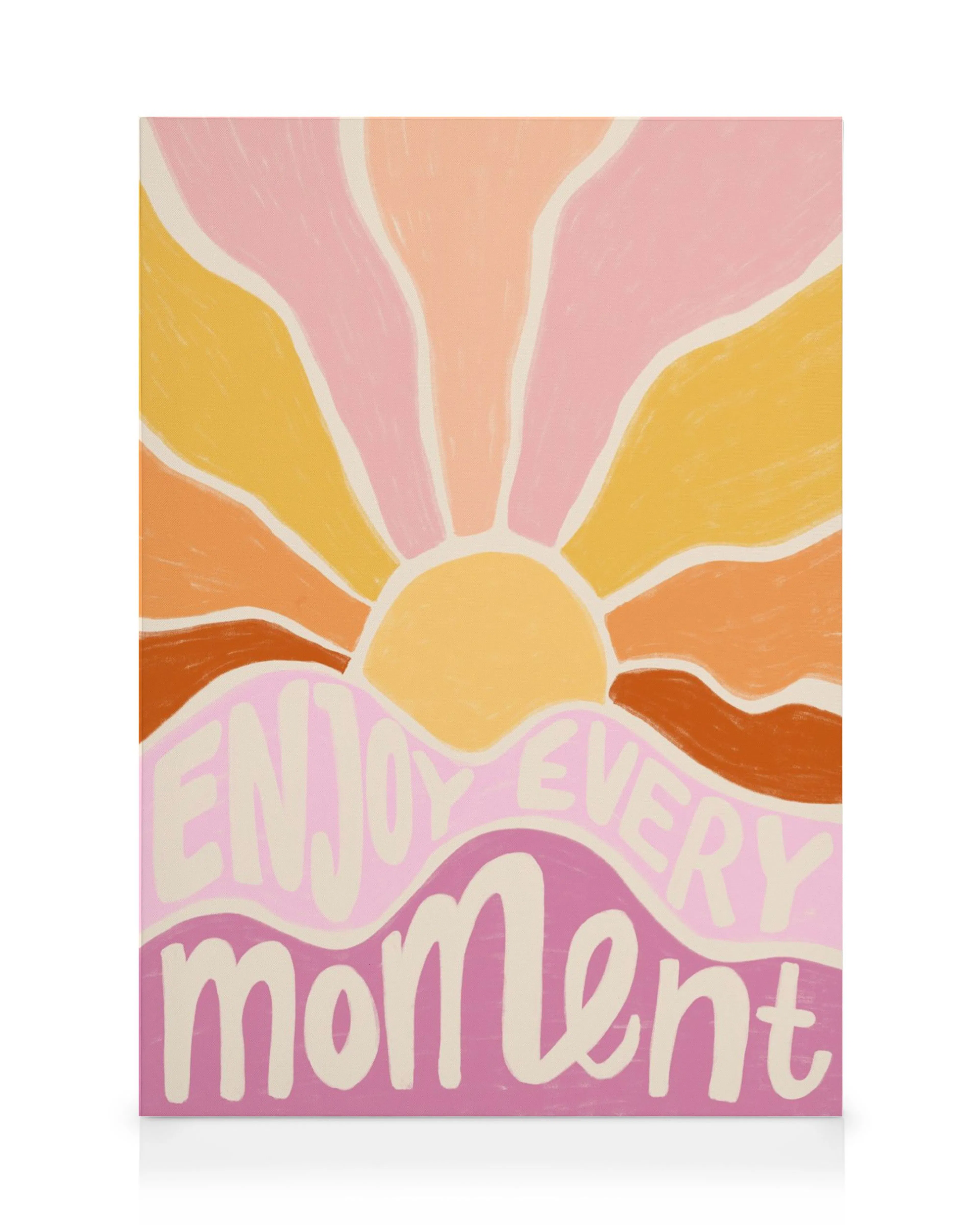 A canvas print featuring a vibrant sunset with Enjoy Every Moment in playful cursive on pink and purple waves.