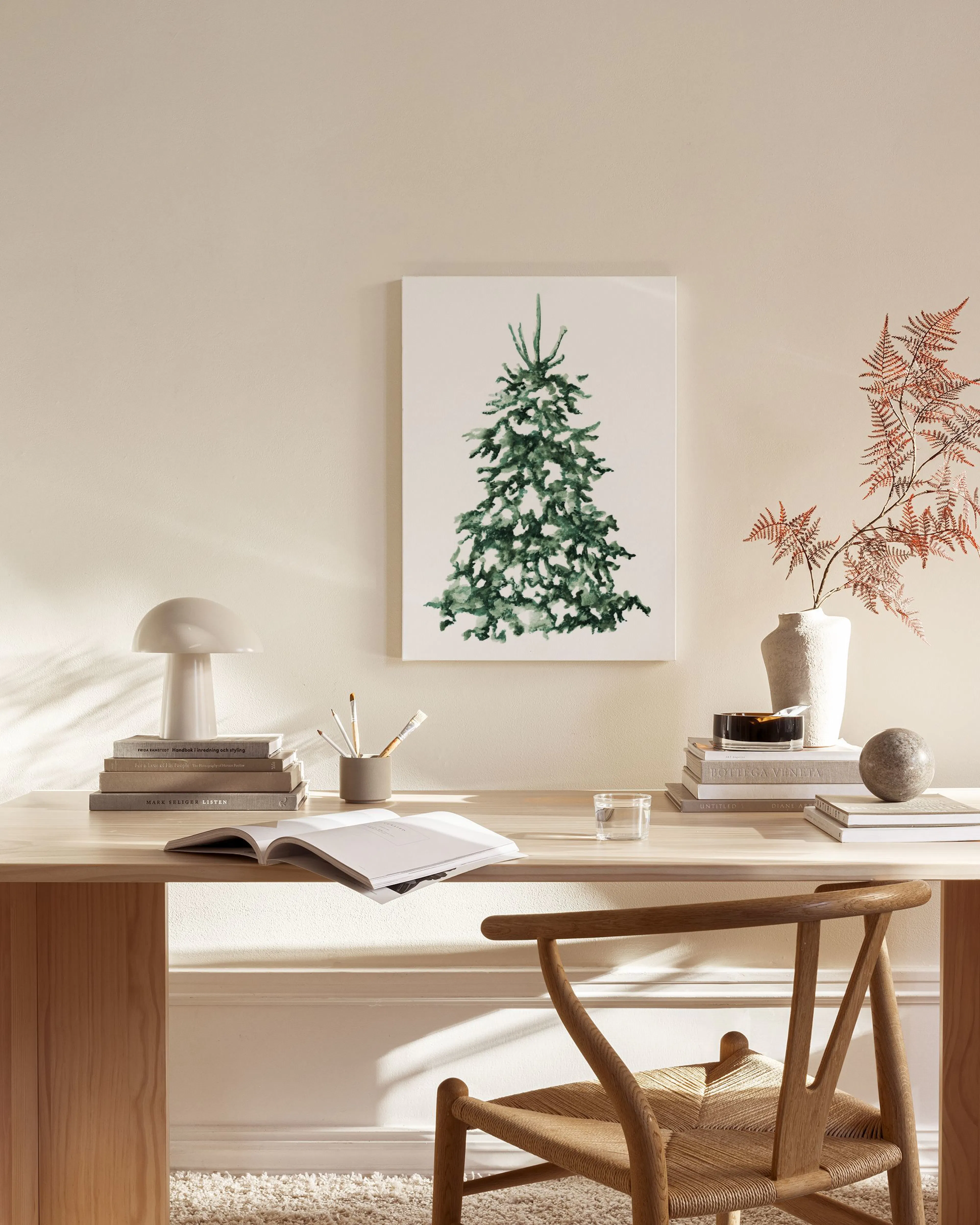Lerretsbilde av et snødekket juletre i grønt og hvitt, henger over en benk i en lys stue.