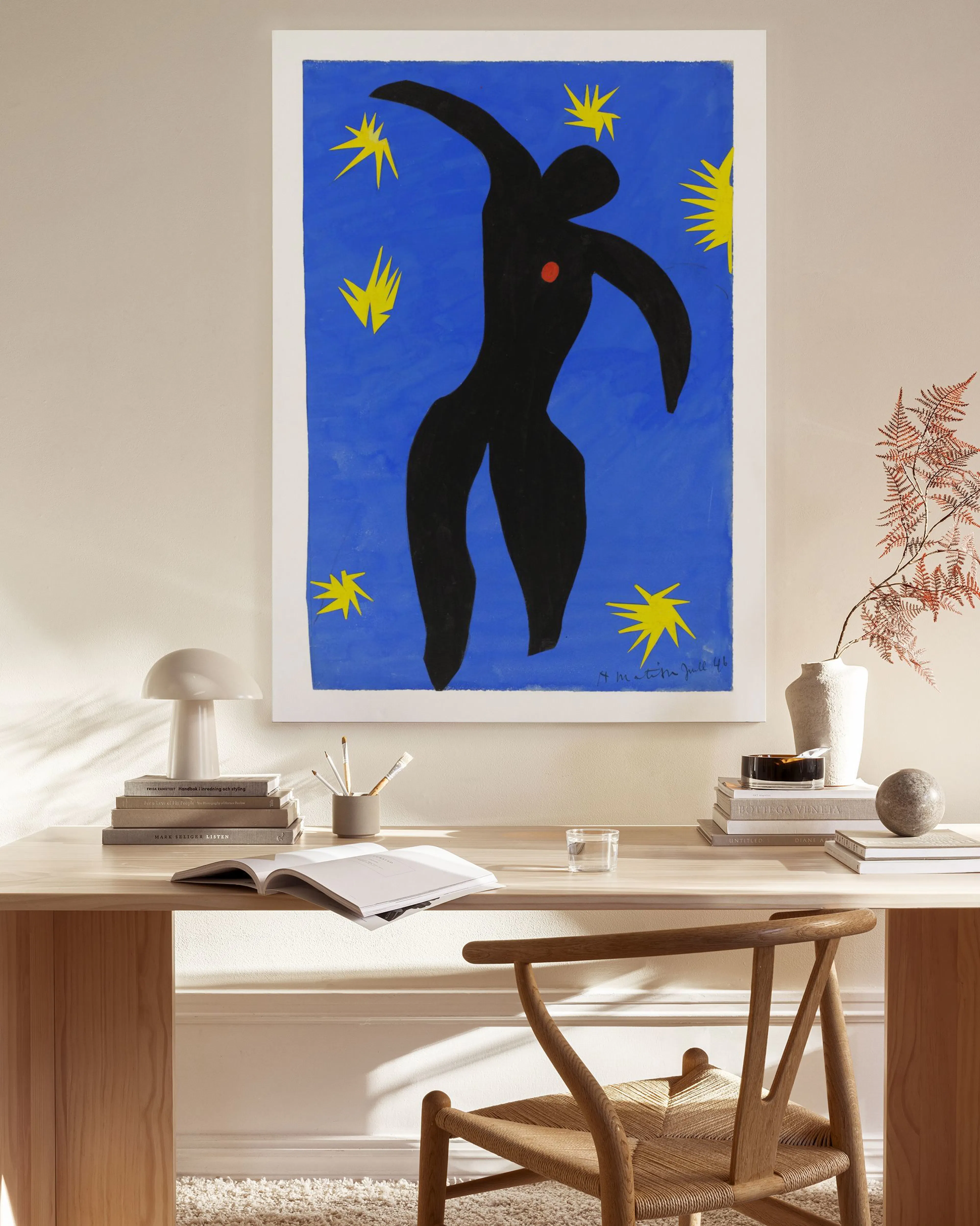 A canvas print of a black dancing figure with a red heart on a blue background with yellow stars, hanging in a modern living roo