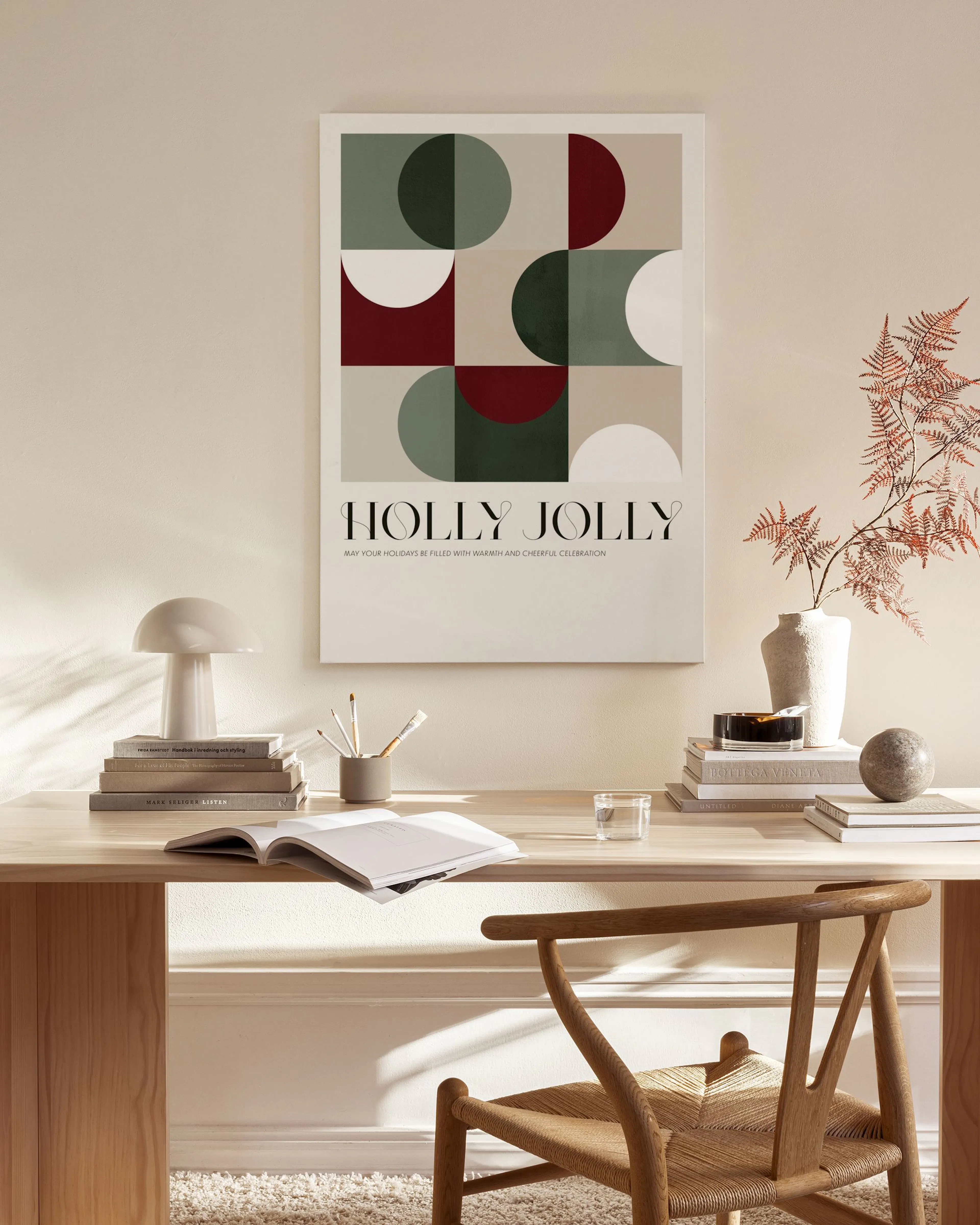 A canvas print with geometric shapes in red, green, and beige, and the text HOLLY JOLLY, hanging in a modern living room.