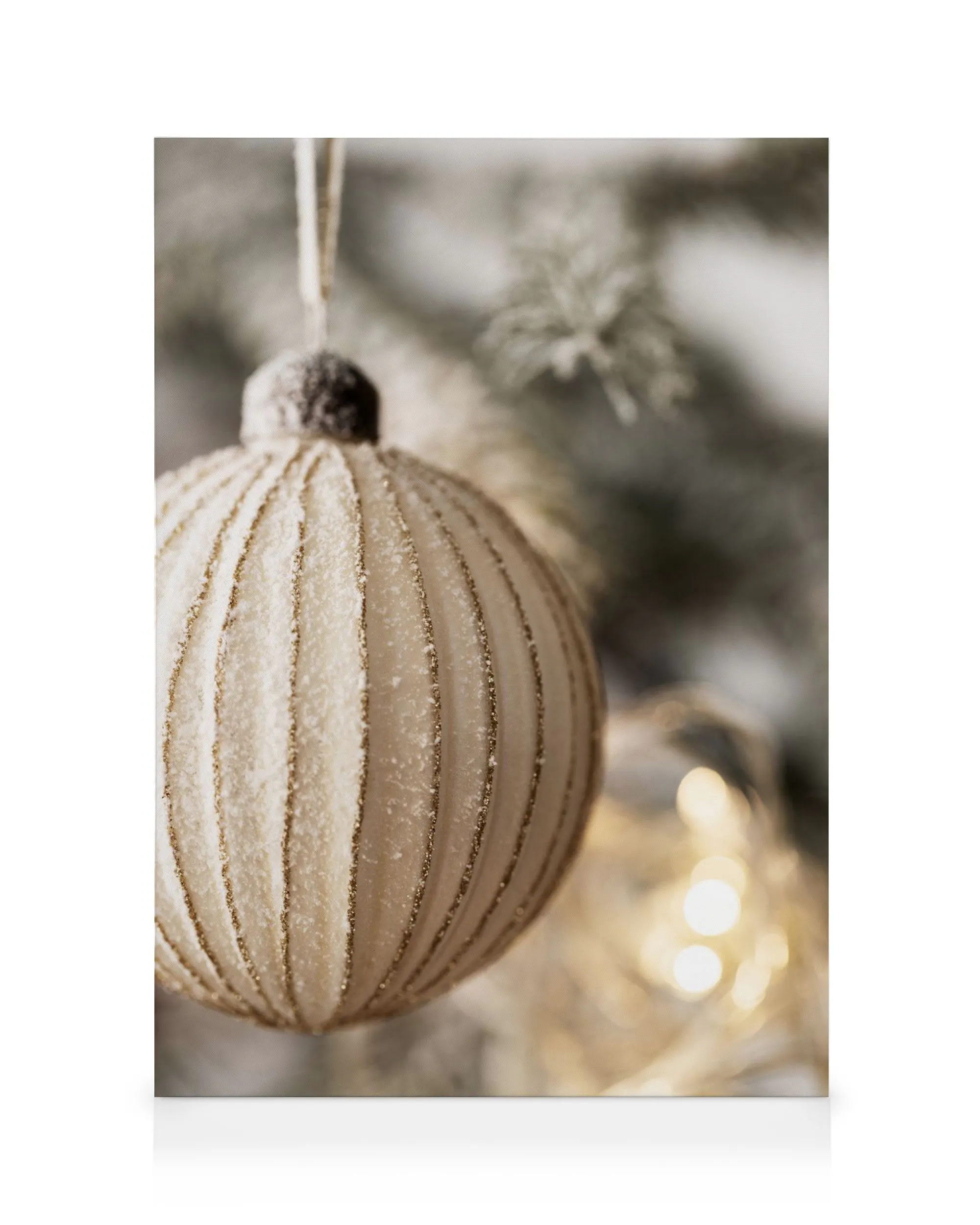 Golden Christmas bauble canvas print, textured with glitter stripes, hanging from a frosted pine branch, with warm bokeh lights.