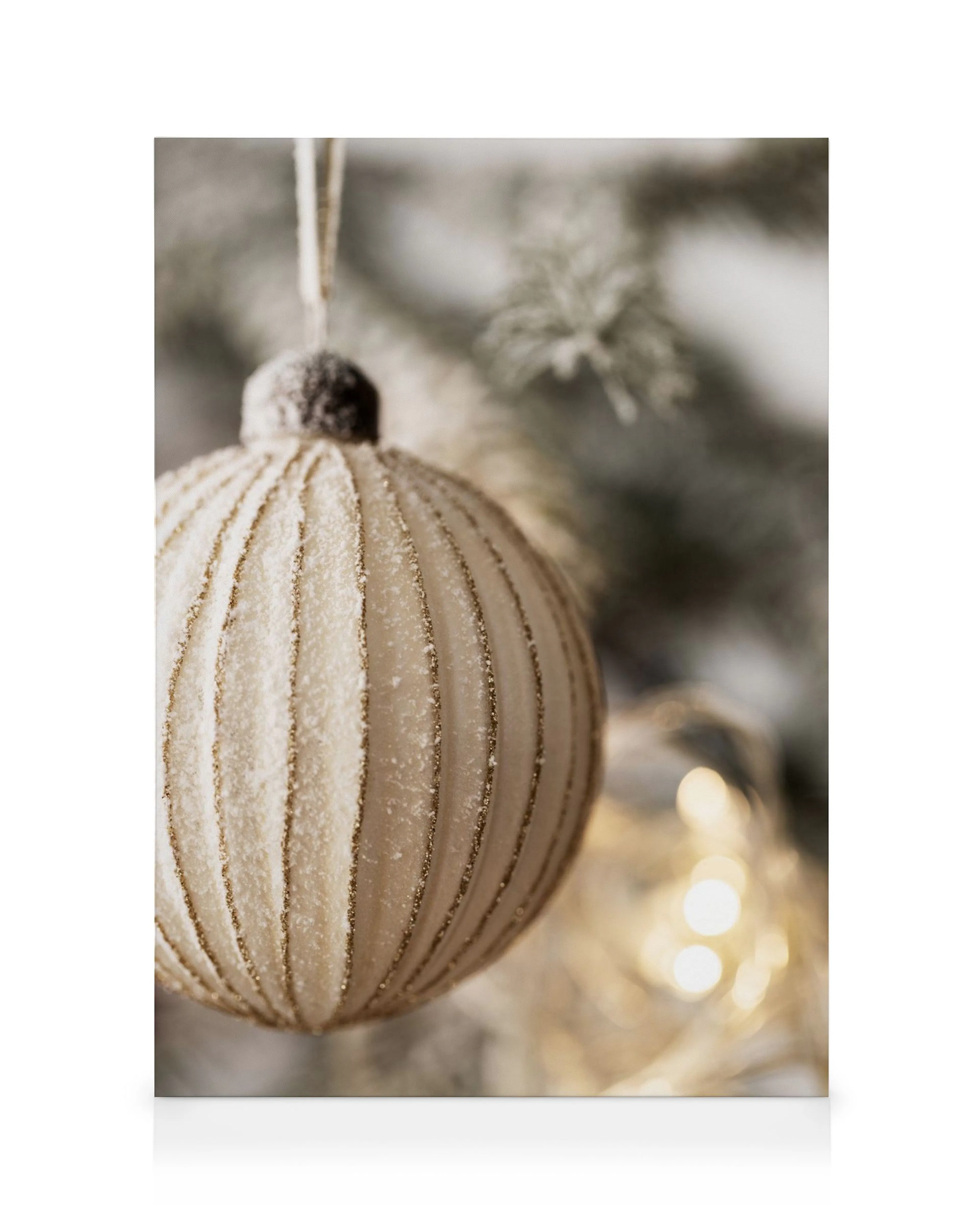 Golden Christmas bauble canvas print, textured with glitter stripes, hanging from a frosted pine branch, with warm bokeh lights.
