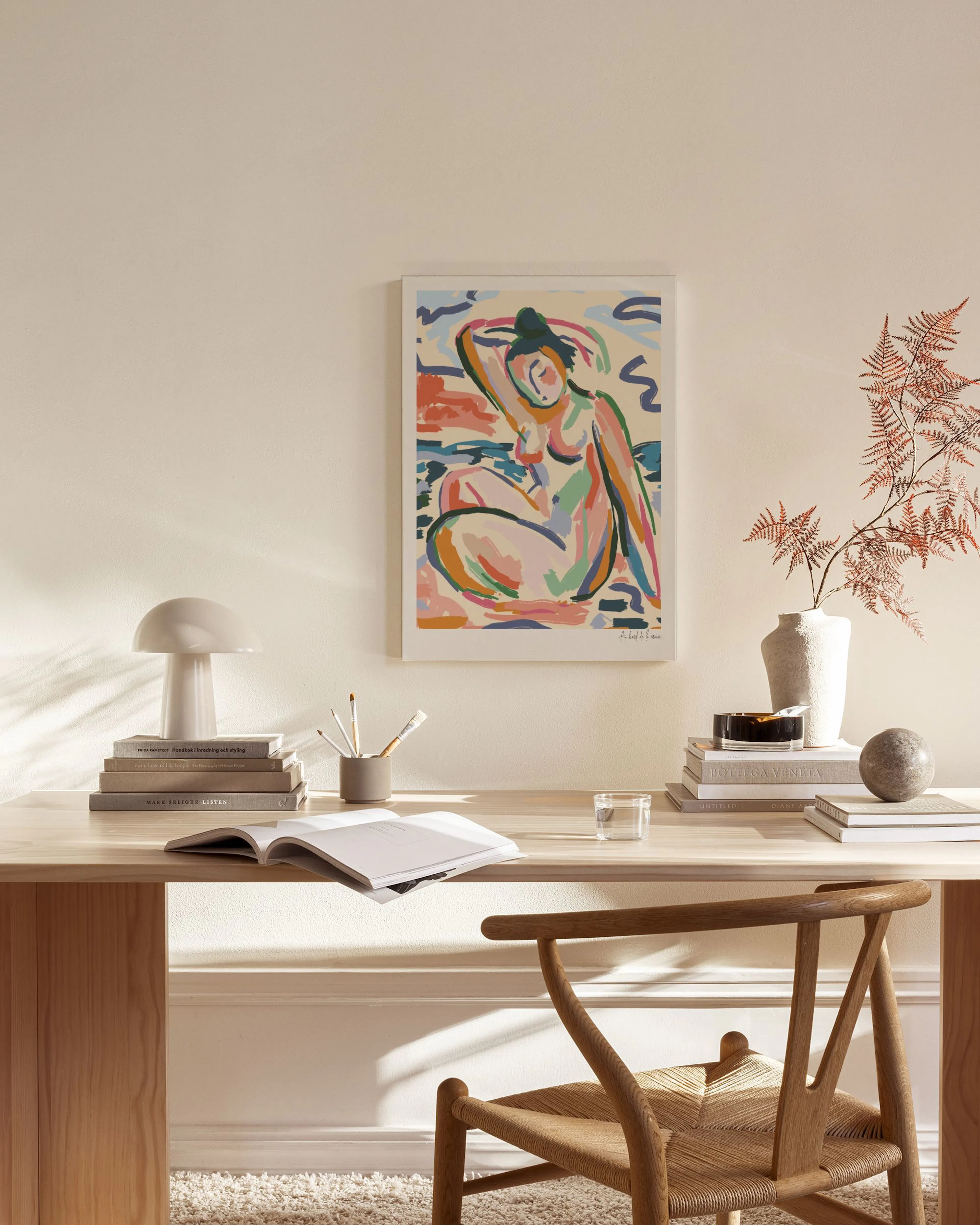 A colorful Matisse-inspired figure on a canvas print, hanging above a wooden console table in a minimalist living room.