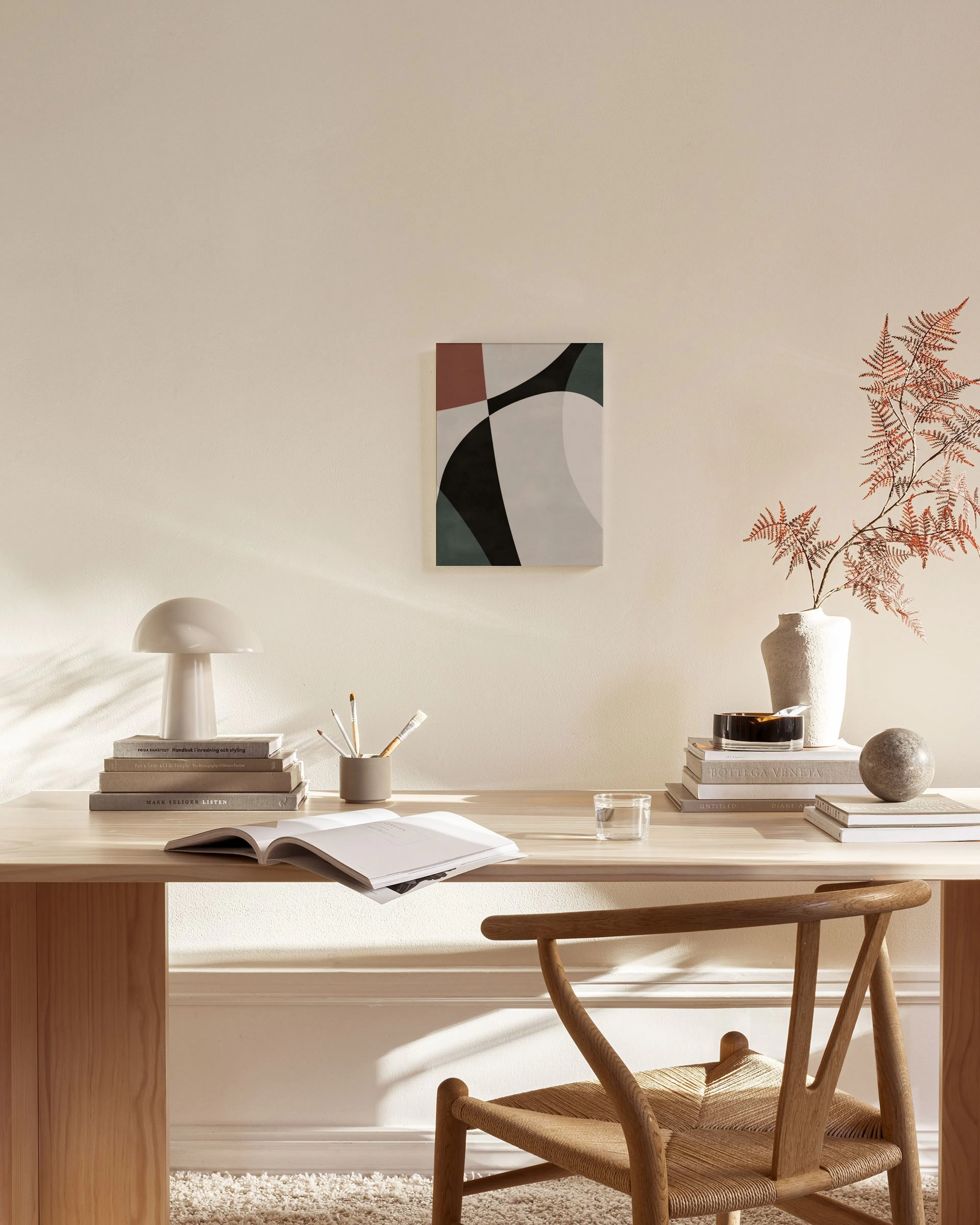 Leinwandbild mit abstrakten Formen in Rotbraun, Schwarz und Petrol, über einem Holzregal in einem hellen Wohnzimmer.